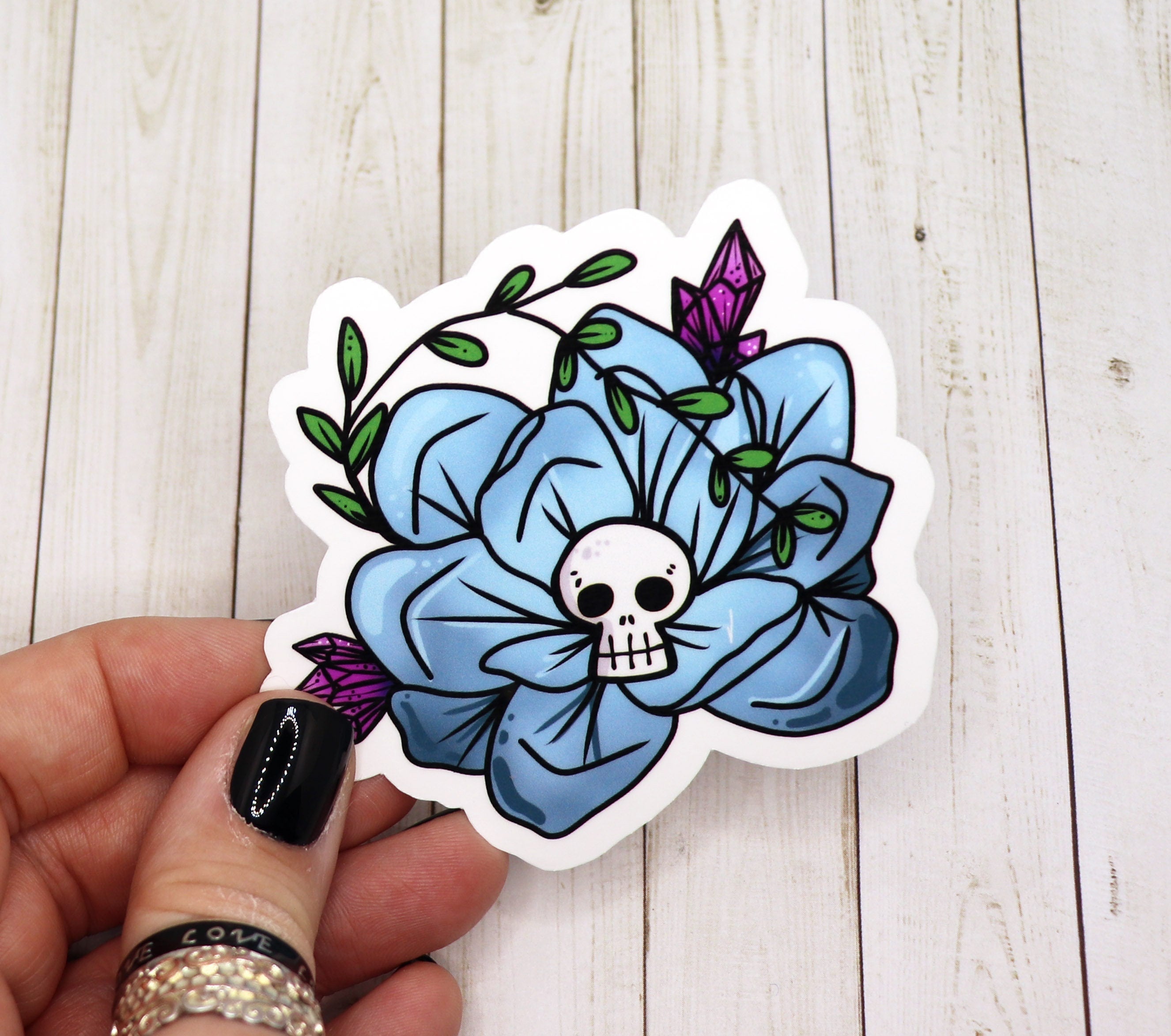 A vibrant blue skull flower sticker on a white background, showcasing intricate floral details and a striking skull design.