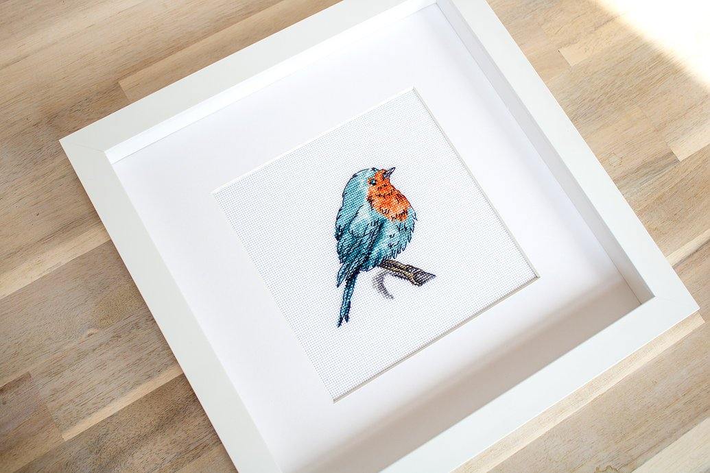 Bluebird B1167L Counted Cross-Stitch Kit featuring colorful threads, Zweigart fabric, and detailed instructions for stitching a charming bird design.