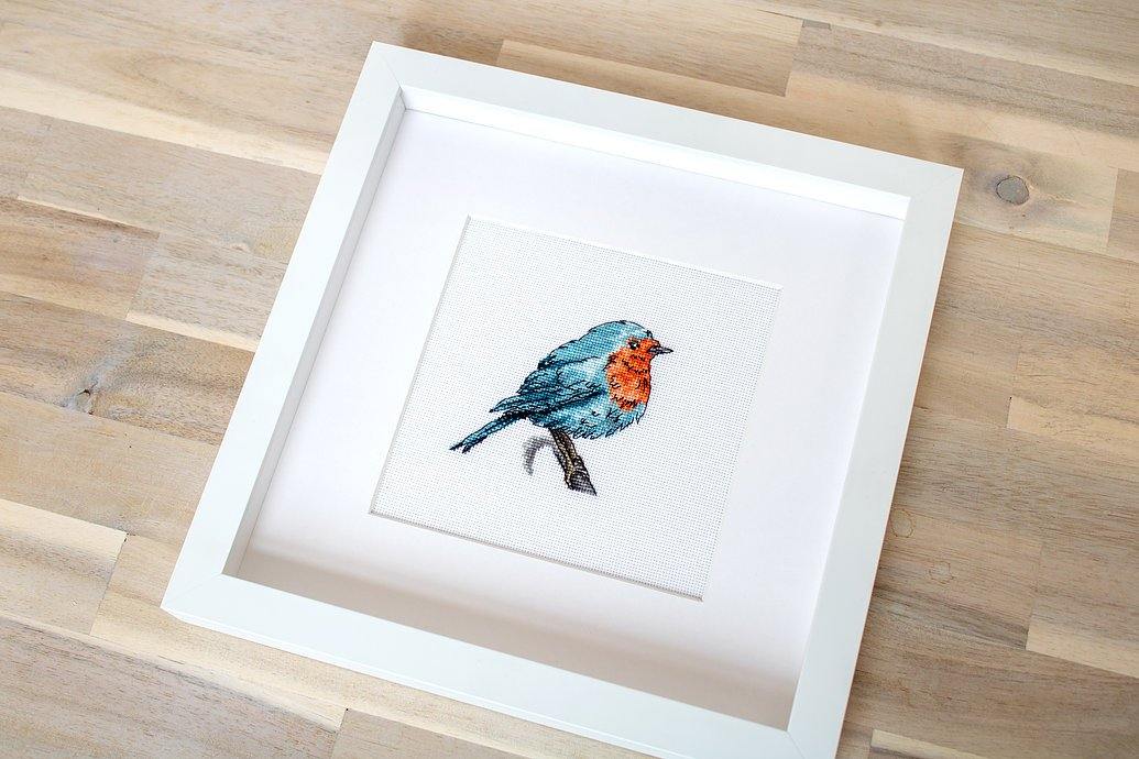 Bluebird B1167L Counted Cross-Stitch Kit featuring colorful threads, Zweigart fabric, and detailed instructions for stitching a charming bird design.