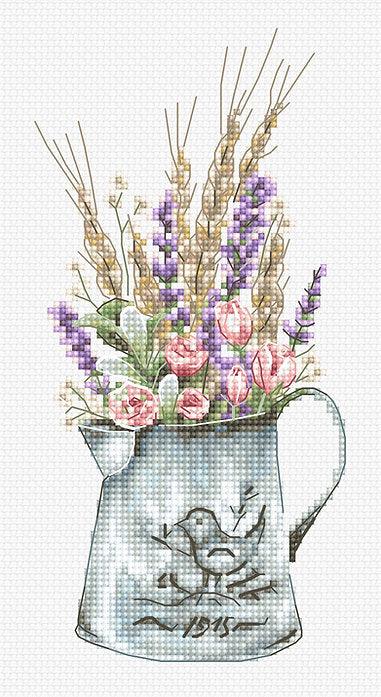 A counted cross-stitch kit featuring a bouquet of lavender and roses in a watering can, showcasing vibrant colors and intricate design.