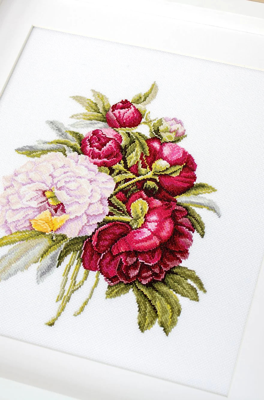 A counted cross-stitch kit featuring a beautiful peony bouquet design, including canvas, colorful threads, needle, and instructions.