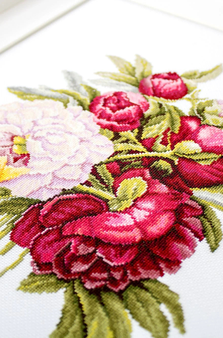 A counted cross-stitch kit featuring a beautiful peony bouquet design, including canvas, colorful threads, needle, and instructions.