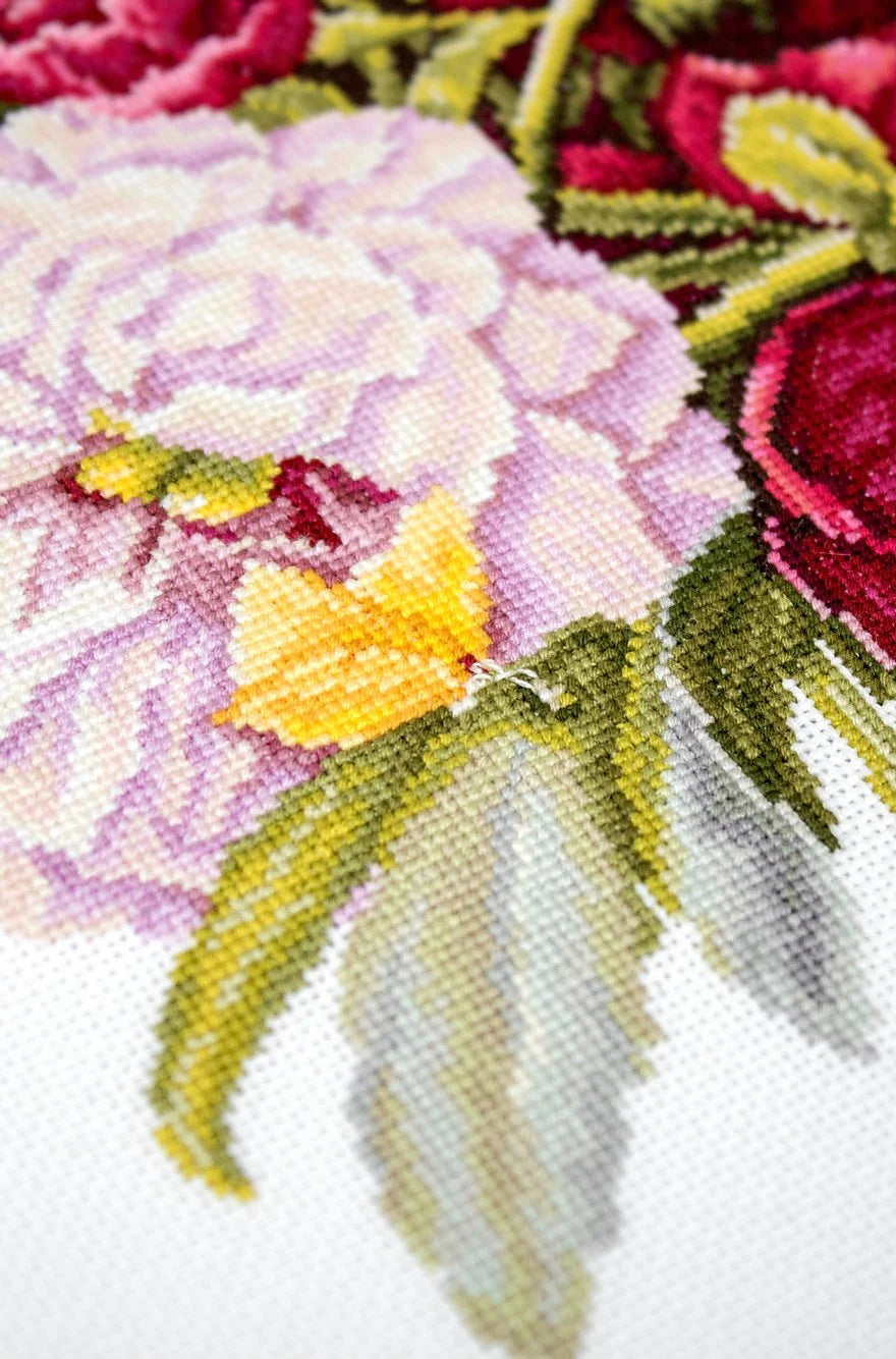 A counted cross-stitch kit featuring a beautiful peony bouquet design, including canvas, colorful threads, needle, and instructions.