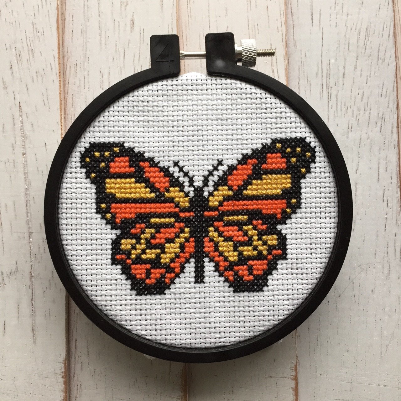 A vibrant counted cross stitch kit featuring a black, yellow, and orange butterfly design, complete with all necessary supplies for crafting.