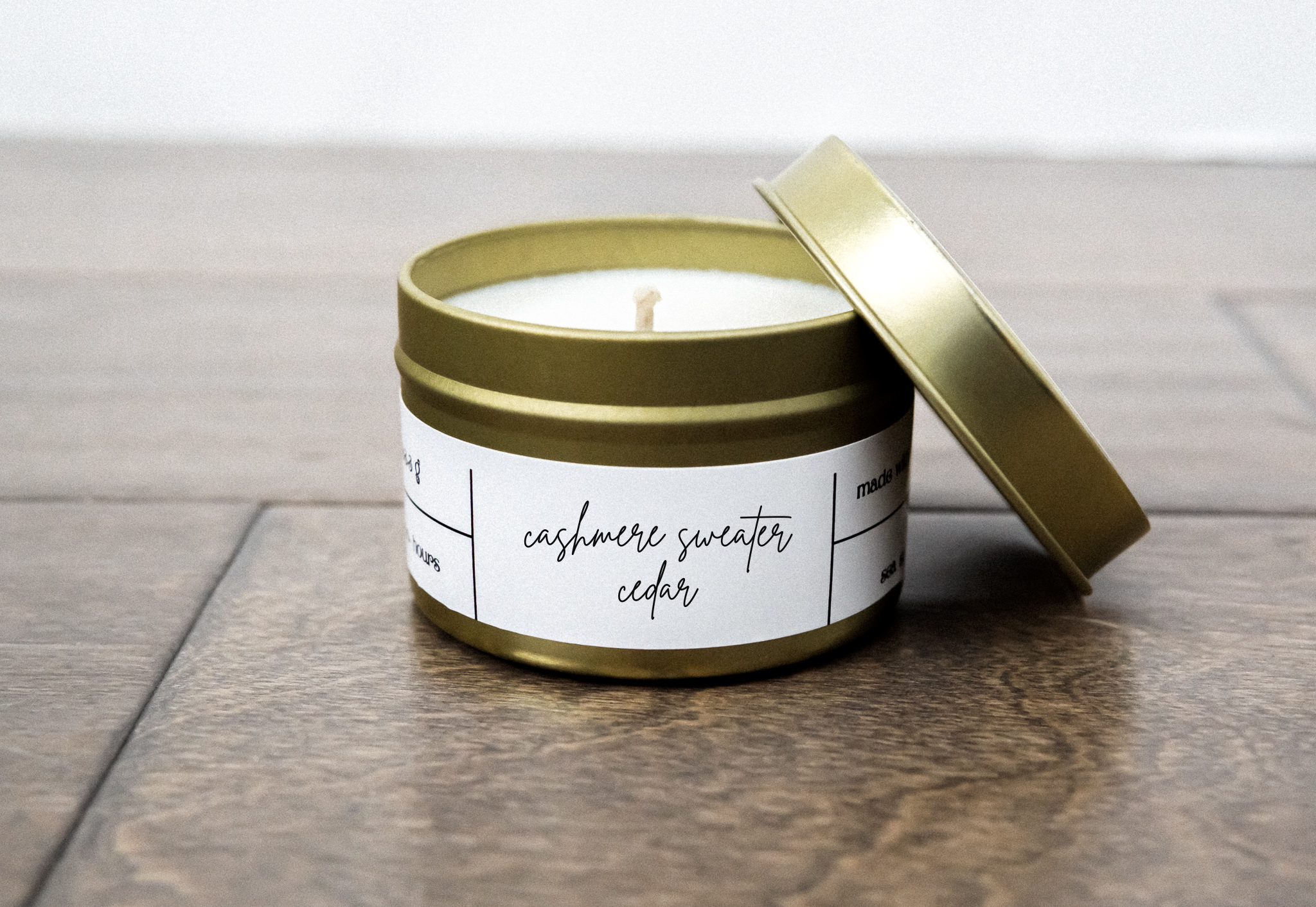 A luxurious Cashmere Sweater & Cedar Gold Travel Candle in a gold tin jar, showcasing its elegant design and inviting fragrance.