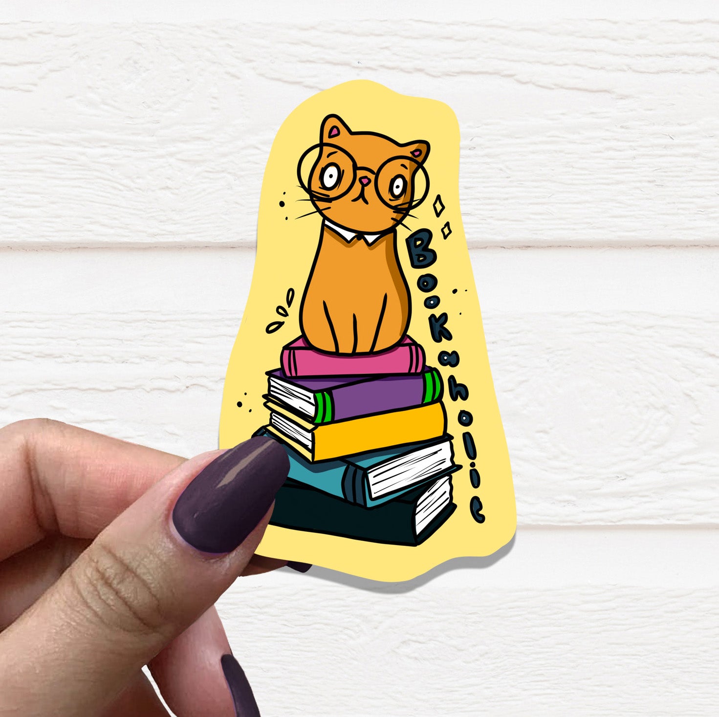 A colorful Cat Bookaholic Vinyl Sticker featuring a playful cat surrounded by books, perfect for decorating various surfaces.