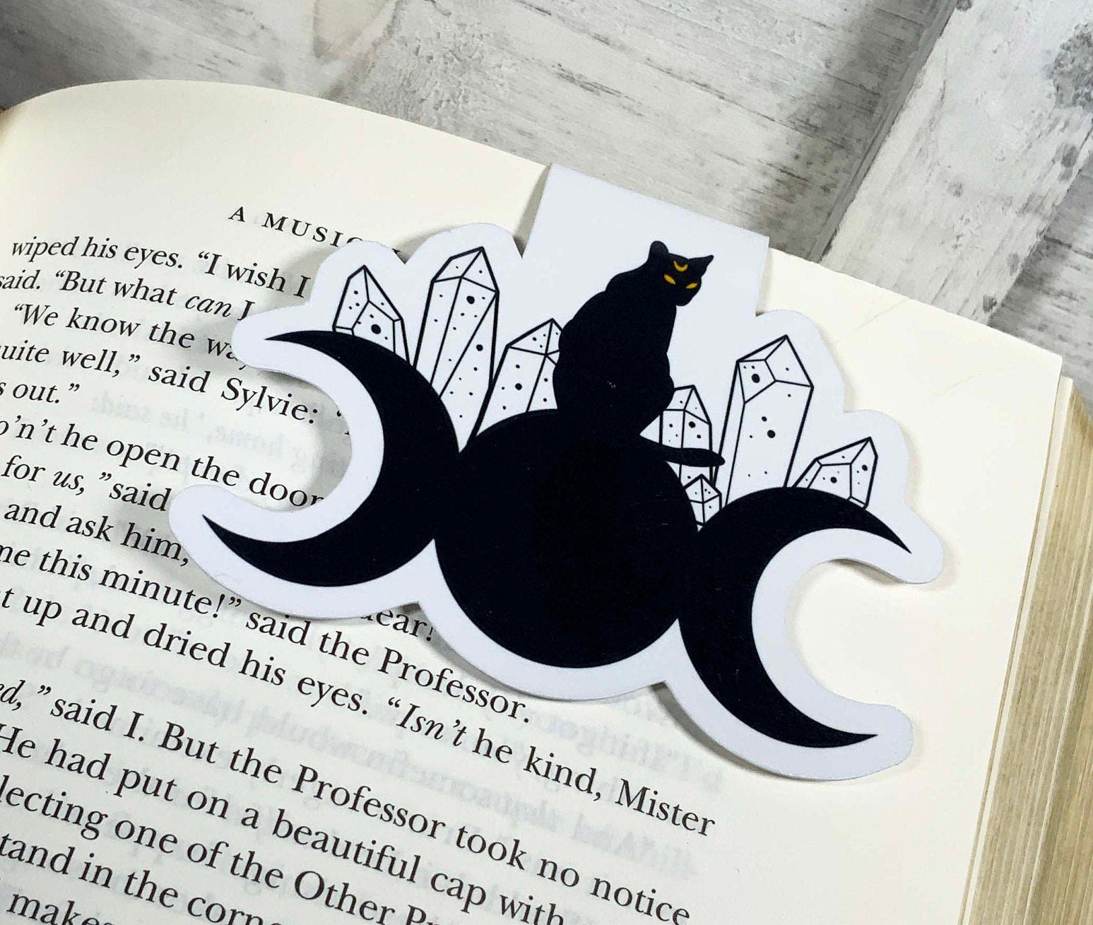 A whimsical Cat on Moons Bookmark featuring a cat design against a moon backdrop, double-sided and laminated for durability.