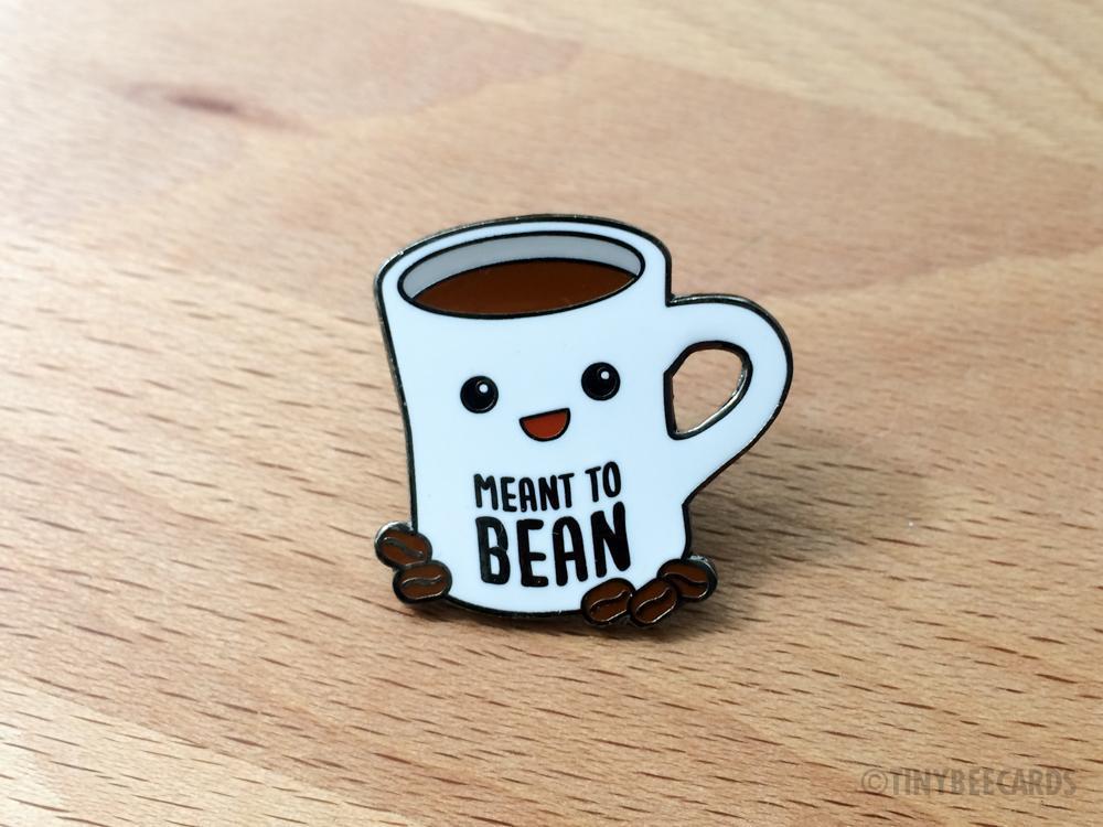 Cute hard enamel pin featuring kawaii coffee cup and coffee beans with pun text 'meant to bean'.