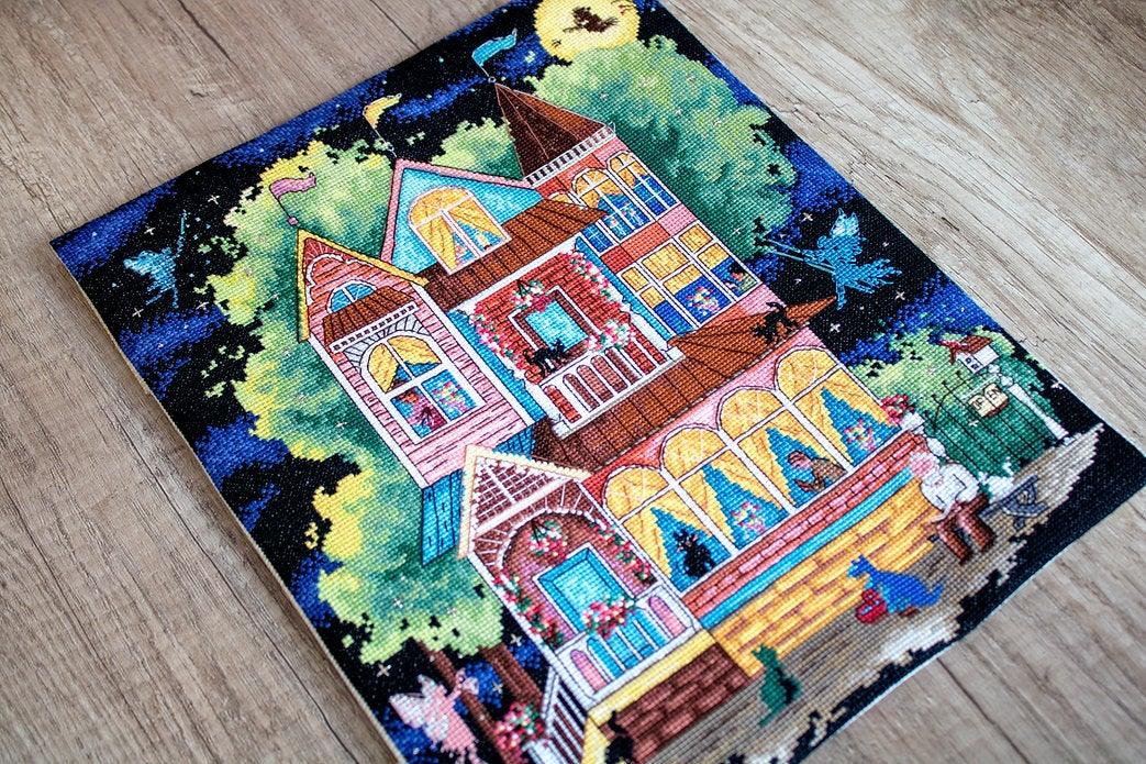 Counted cross stitch kit featuring a fairy tale house design with colorful threads and Aida canvas.