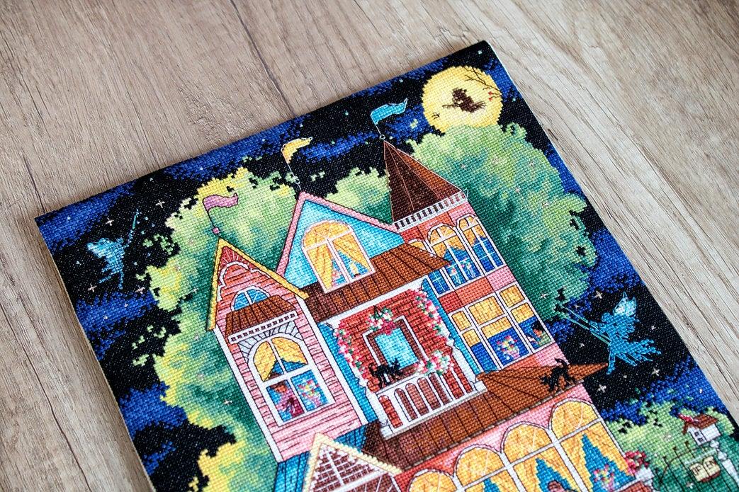 Counted cross stitch kit featuring a fairy tale house design with colorful threads and Aida canvas.