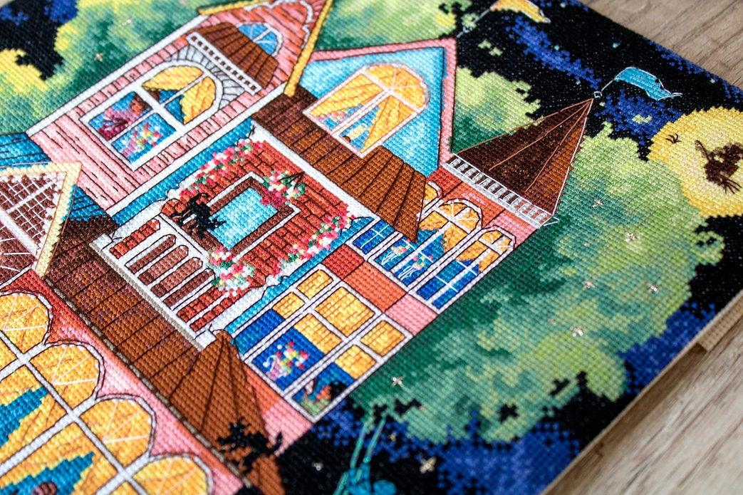 Counted cross stitch kit featuring a fairy tale house design with colorful threads and Aida canvas.