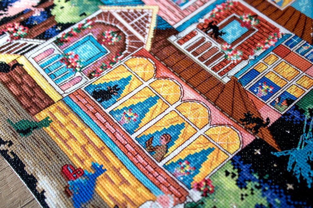 Counted cross stitch kit featuring a fairy tale house design with colorful threads and Aida canvas.