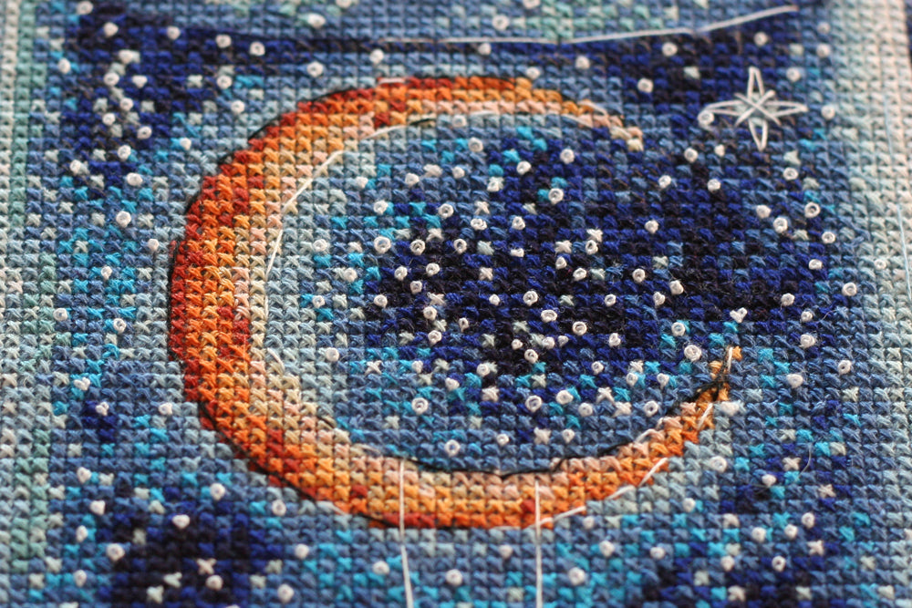 Cross-stitch kit A month for lovers AH-095 featuring dark blue canvas, colorful floss, and stitching supplies.