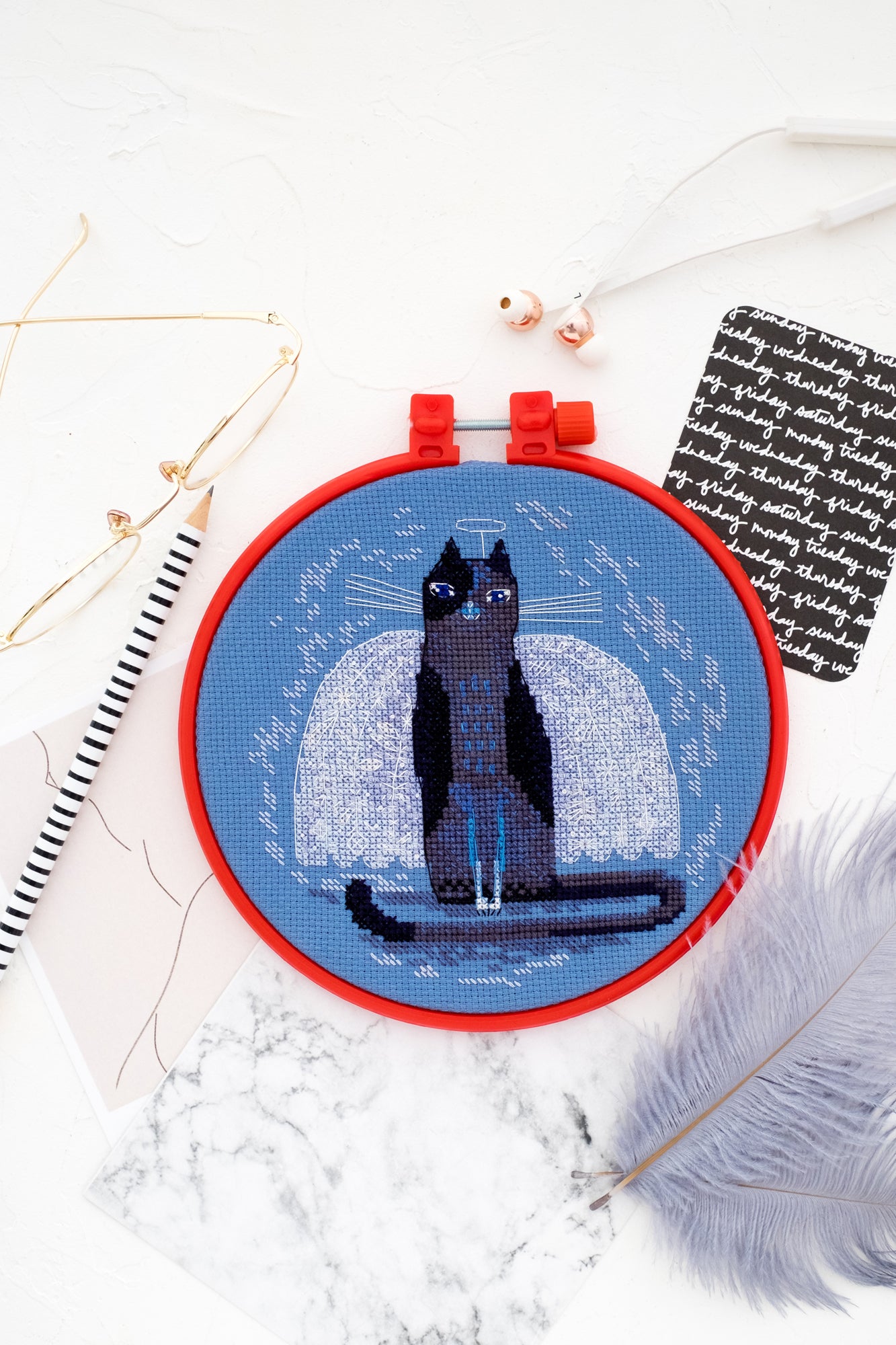 Cross-stitch kit Cat AHM-019 featuring a blue cotton canvas, needles, and colorful floss organized neatly.