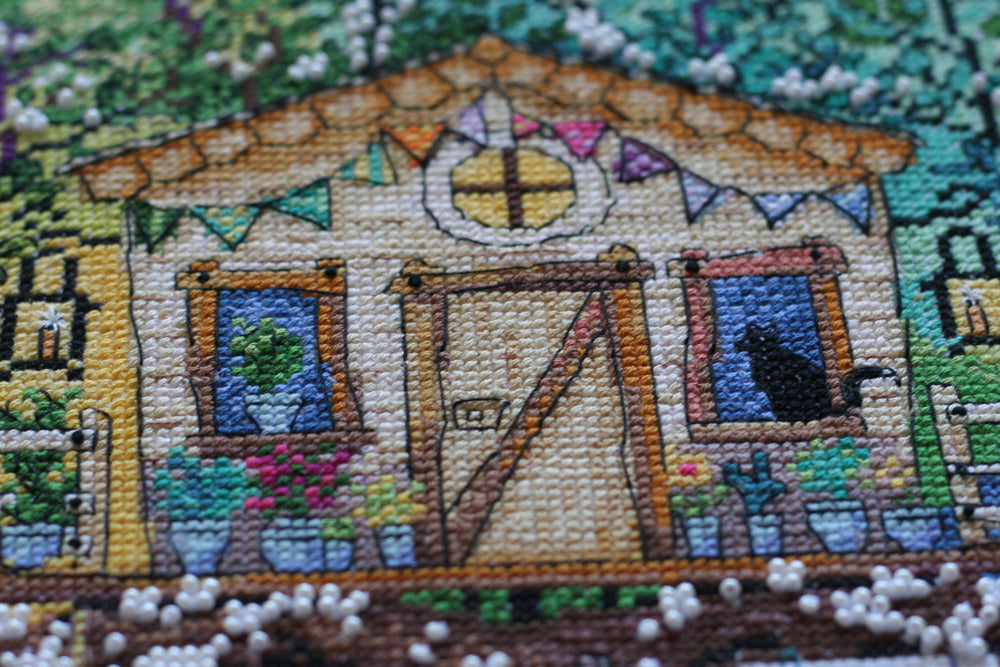 Cross-stitch kit featuring a cat house design with colorful threads and beads, perfect for crafting enthusiasts.