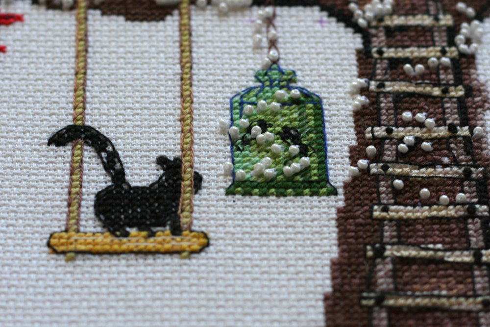 Cross-stitch kit featuring a cat house design with colorful threads and beads, perfect for crafting enthusiasts.