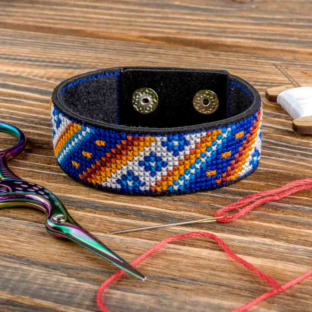 Cross-stitch kit on artificial leather FLHL-039 with materials for creating embroidered bracelets, including cotton floss and needle.