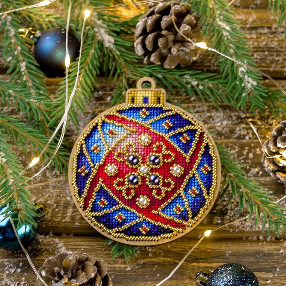 Cross-stitch kit on wood FLW-010 featuring a plywood blank, colorful threads, beads, and crafting tools for creating Christmas tree decorations.