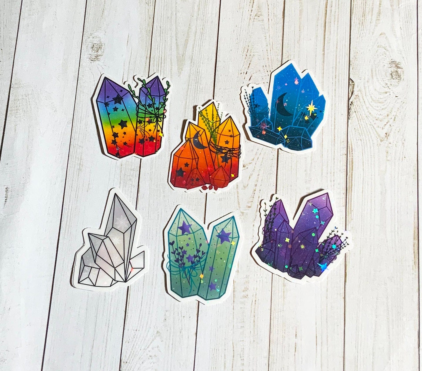 A vibrant Crystal Sticker Pack featuring 6 holographic stickers on a matte vinyl background, showcasing their unique designs.