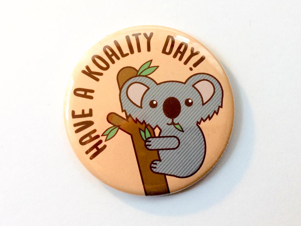 Cute koala magnet or pin featuring a koala in a tree with leaves and the text 'Have a Koality Day'.