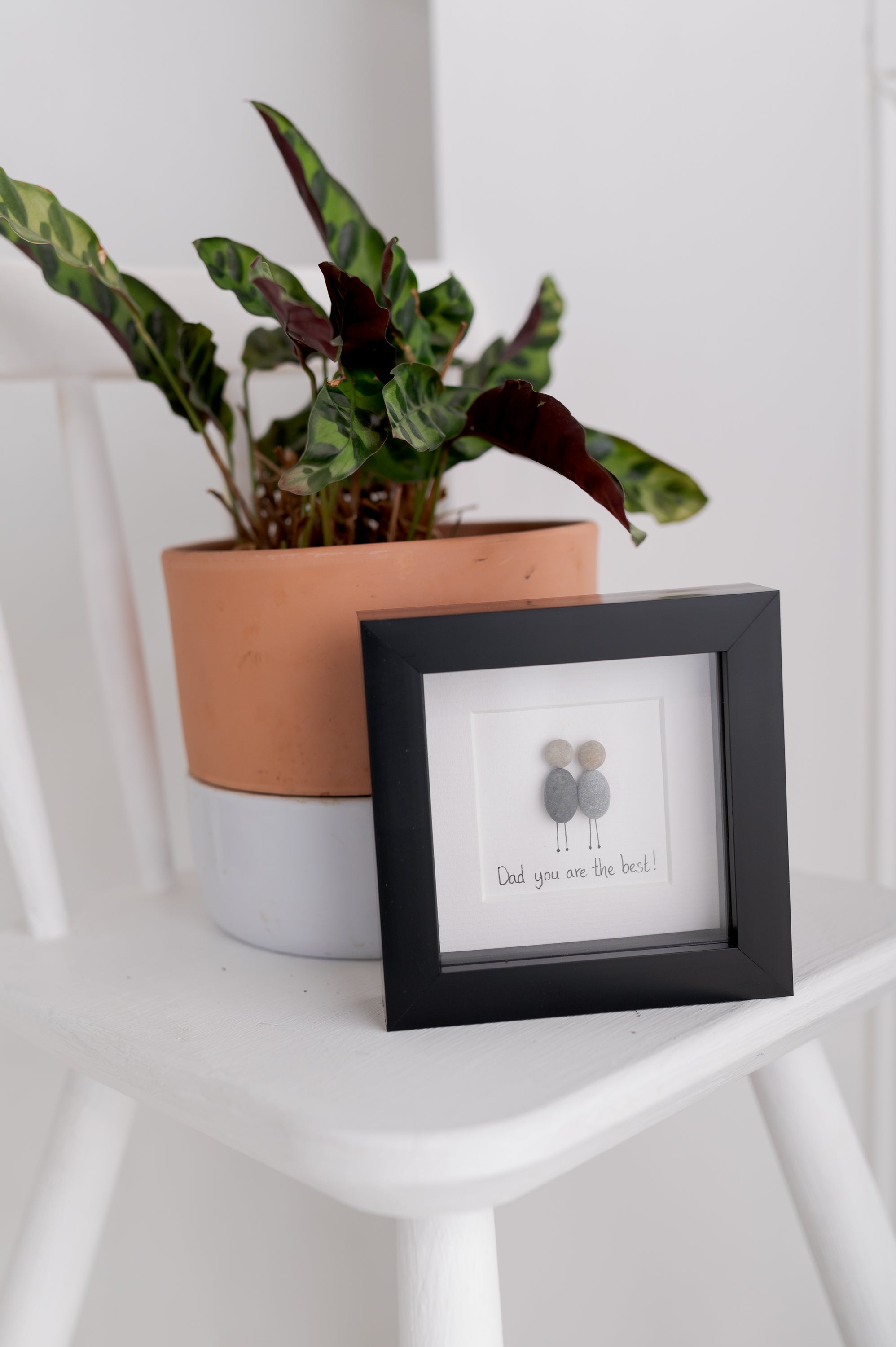 A beautiful pebble picture framed in black or white, celebrating the best dads with a unique design.