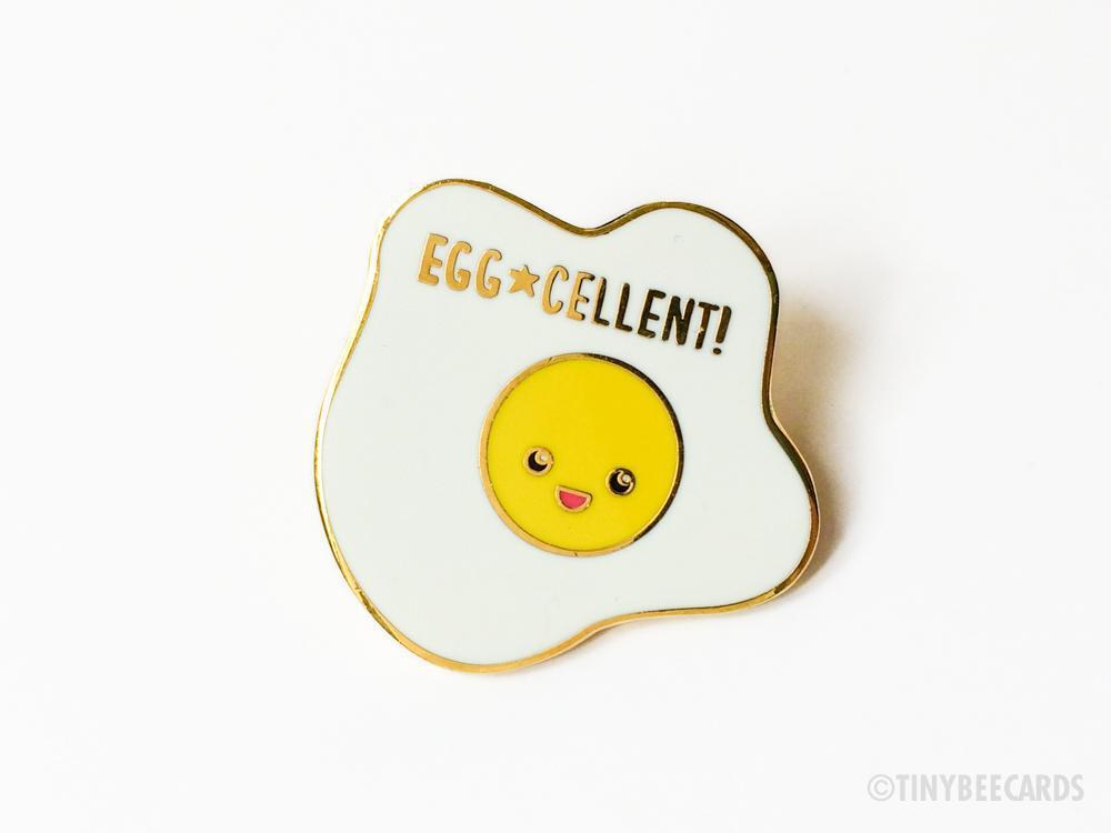 A cute kawaii fried egg hard enamel pin with a gold metal finish, measuring 1.25 inches tall, perfect for accessories.