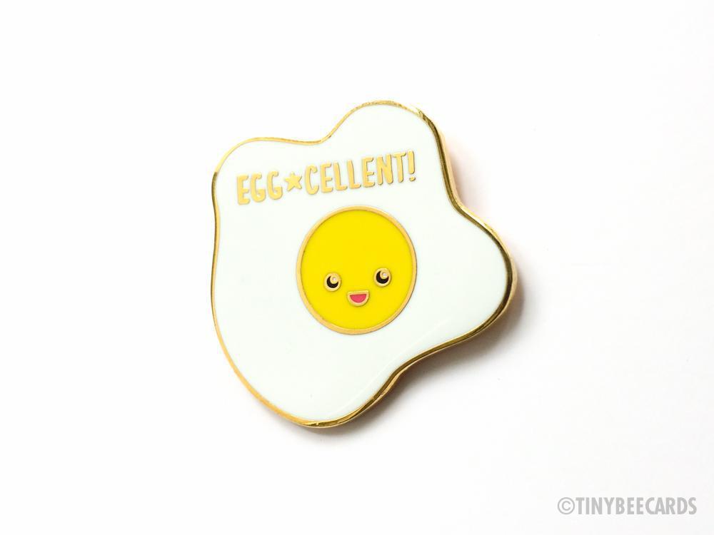 A cute kawaii fried egg hard enamel pin with a gold metal finish, measuring 1.25 inches tall, perfect for accessories.