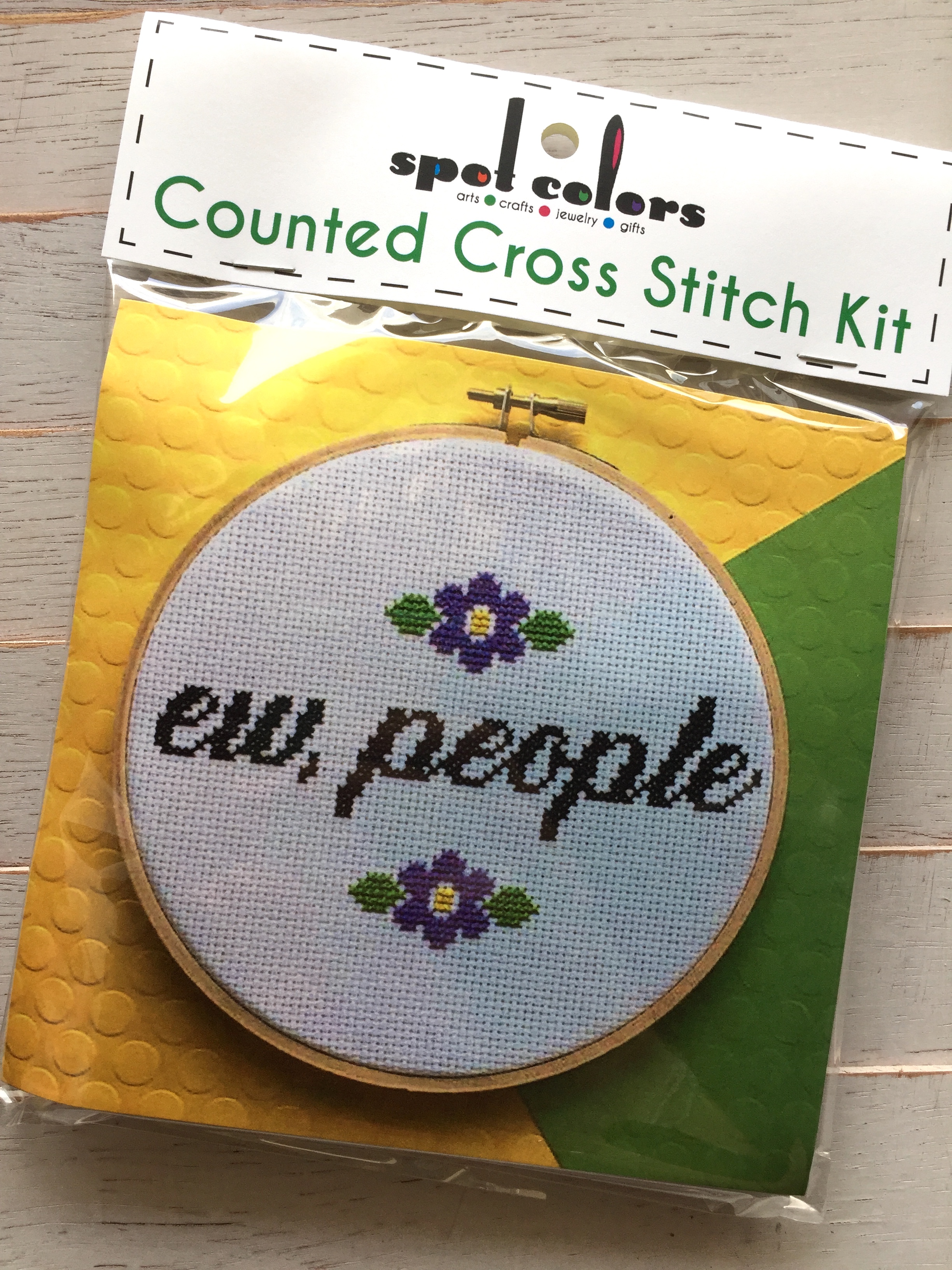 A colorful counted cross stitch kit featuring the phrase 'Ew, People' in cursive surrounded by floral designs, complete with all necessary supplies.