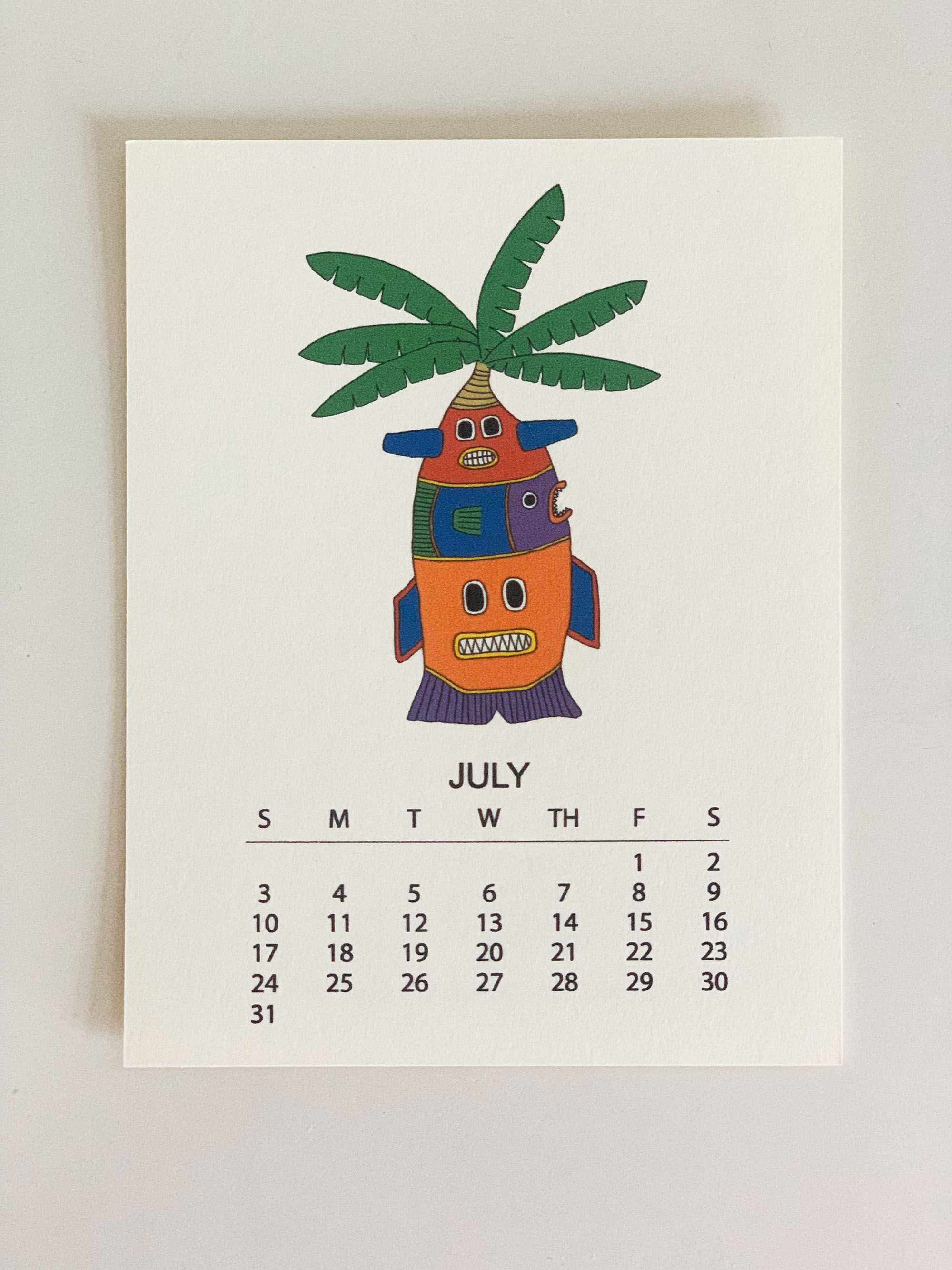 2022 Monthly Desk Calendar featuring original fish totem drawings displayed on a wooden easel.