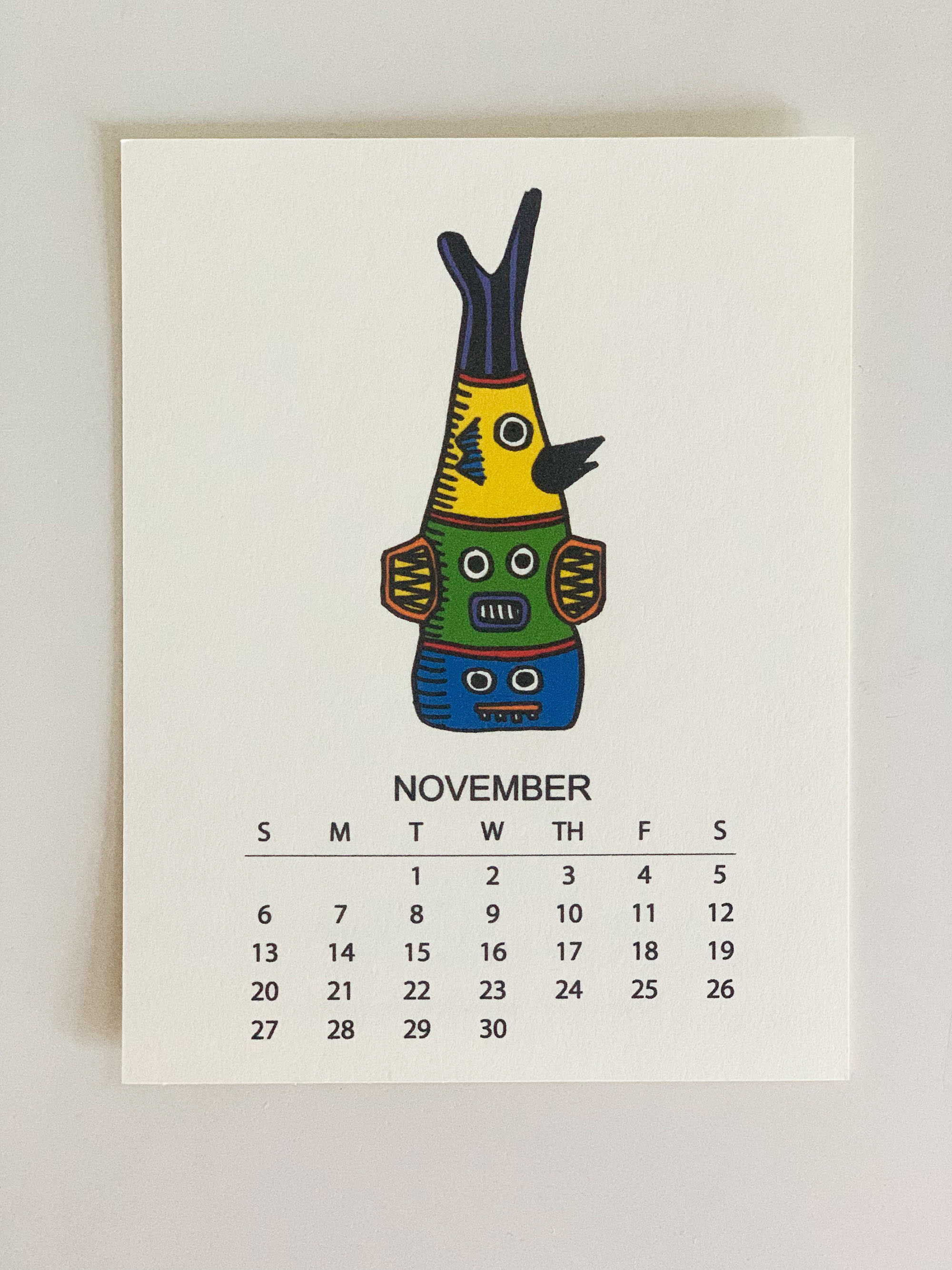 2022 Monthly Desk Calendar featuring original fish totem drawings displayed on a wooden easel.