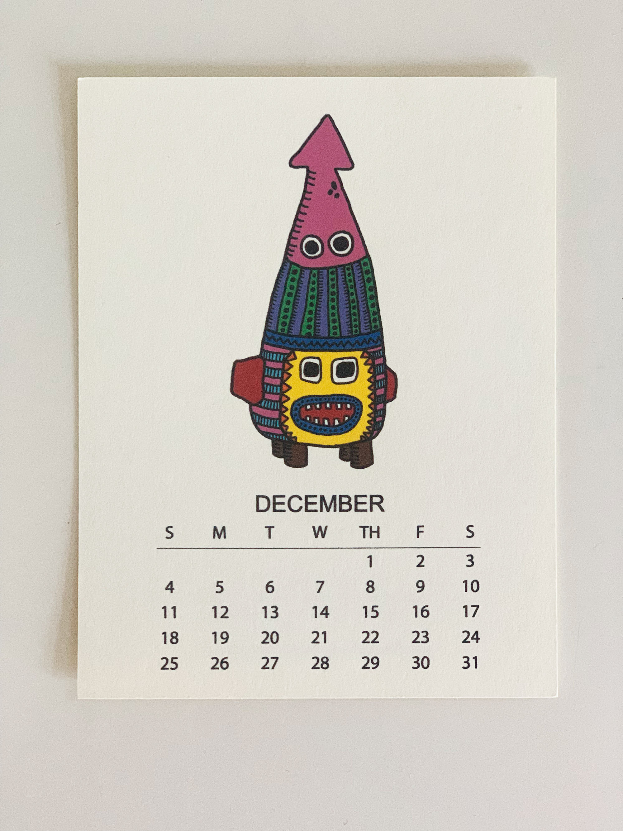 2022 Monthly Desk Calendar featuring original fish totem drawings displayed on a wooden easel.