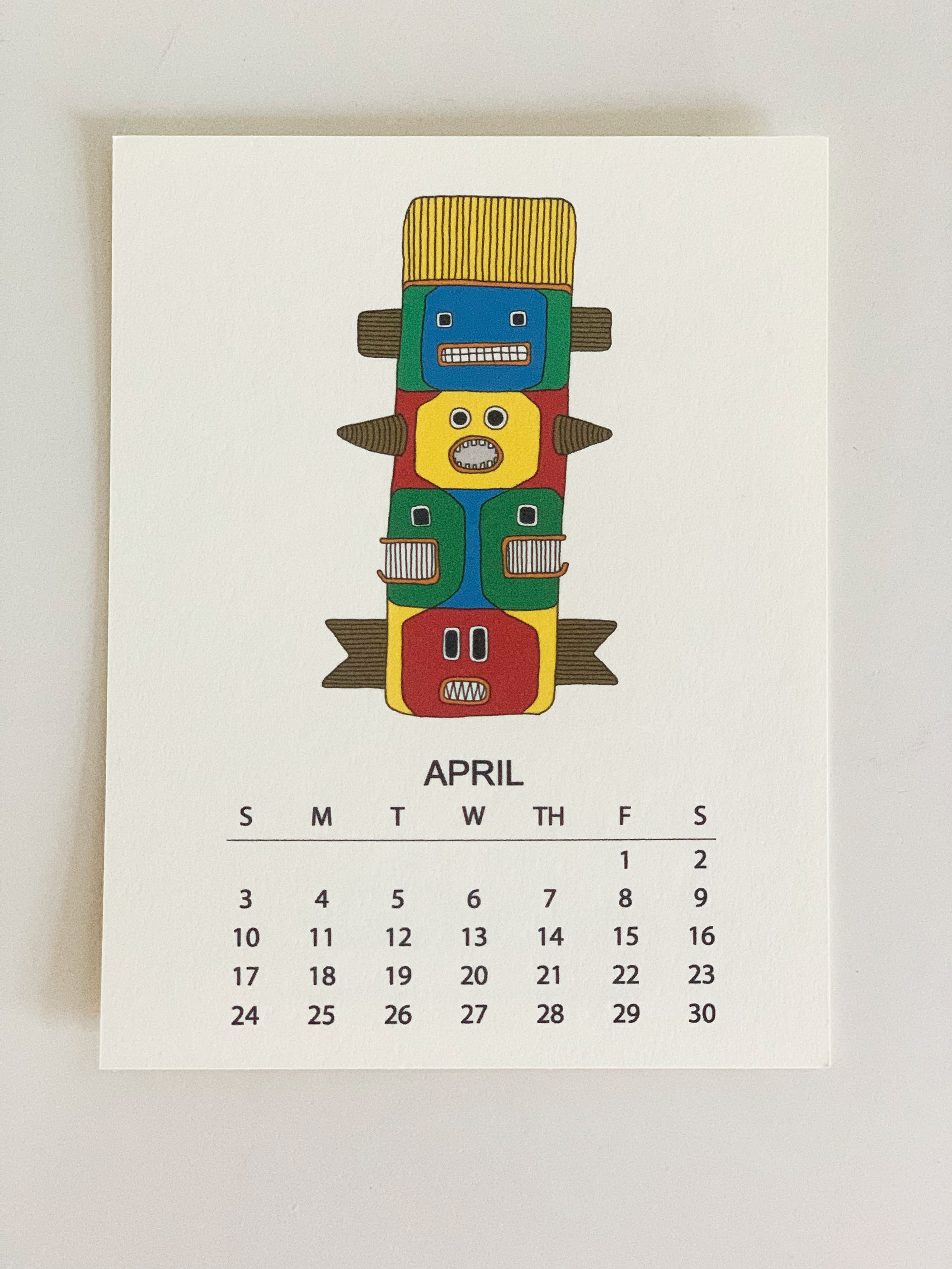 2022 Monthly Desk Calendar featuring original fish totem drawings displayed on a wooden easel.