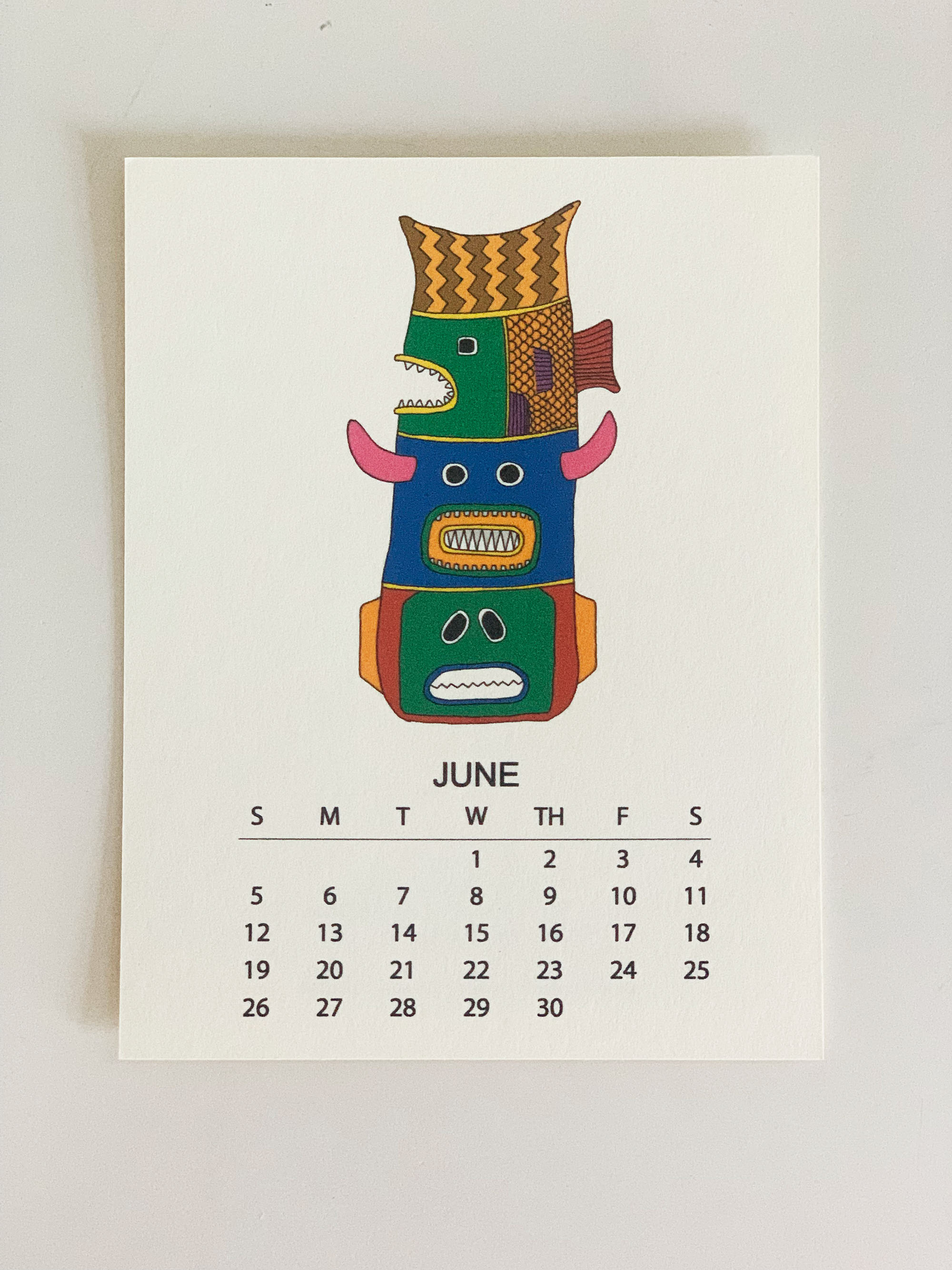 2022 Monthly Desk Calendar featuring original fish totem drawings displayed on a wooden easel.