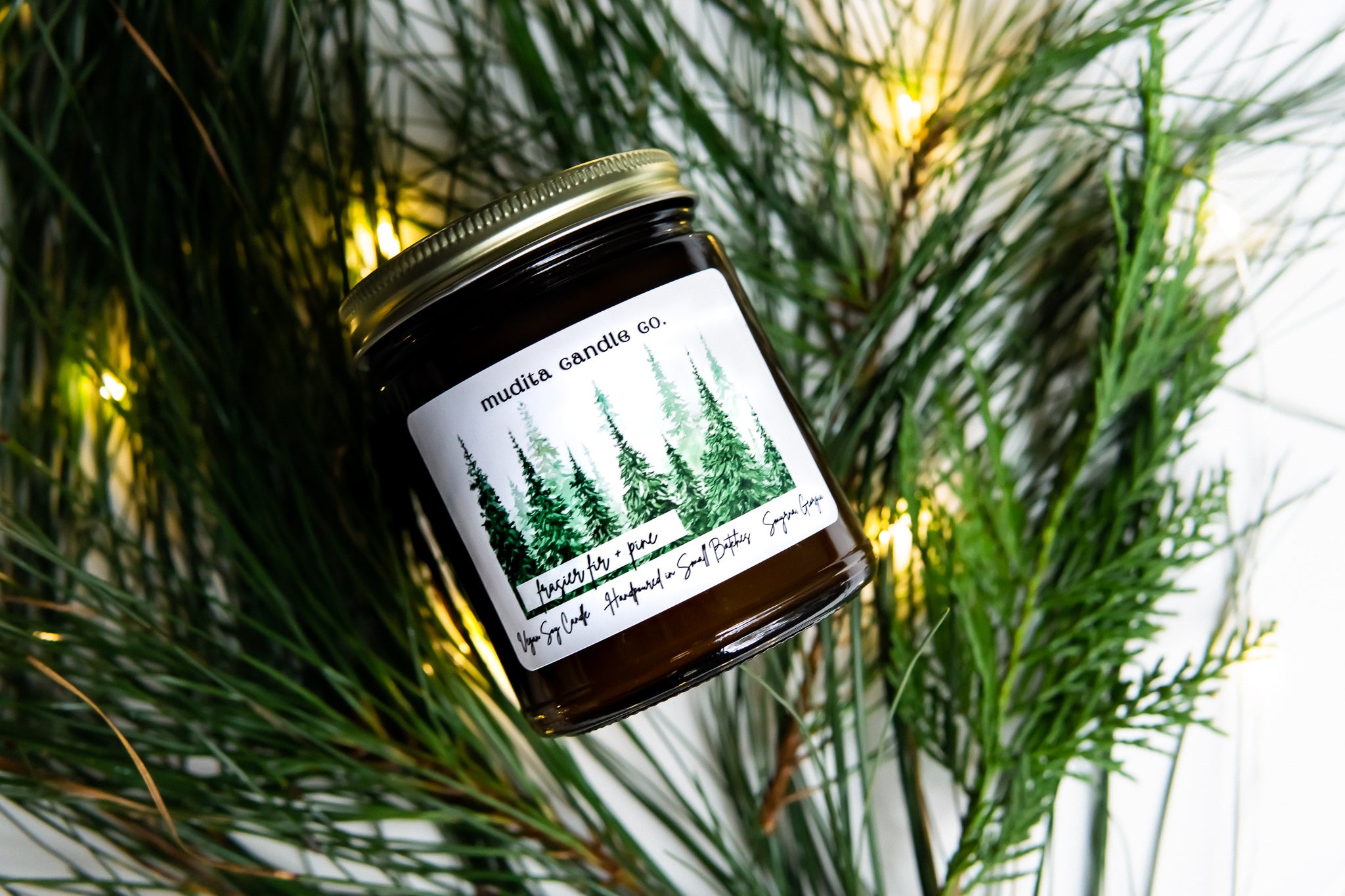 Fraser Fir + Pine candle in amber glass jar with gold lid, showcasing its elegant design and natural ingredients.