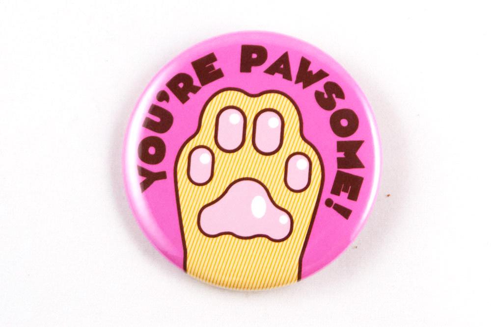 Funny cat paw magnet or pin featuring the phrase 'you're pawsome!' in a playful design.