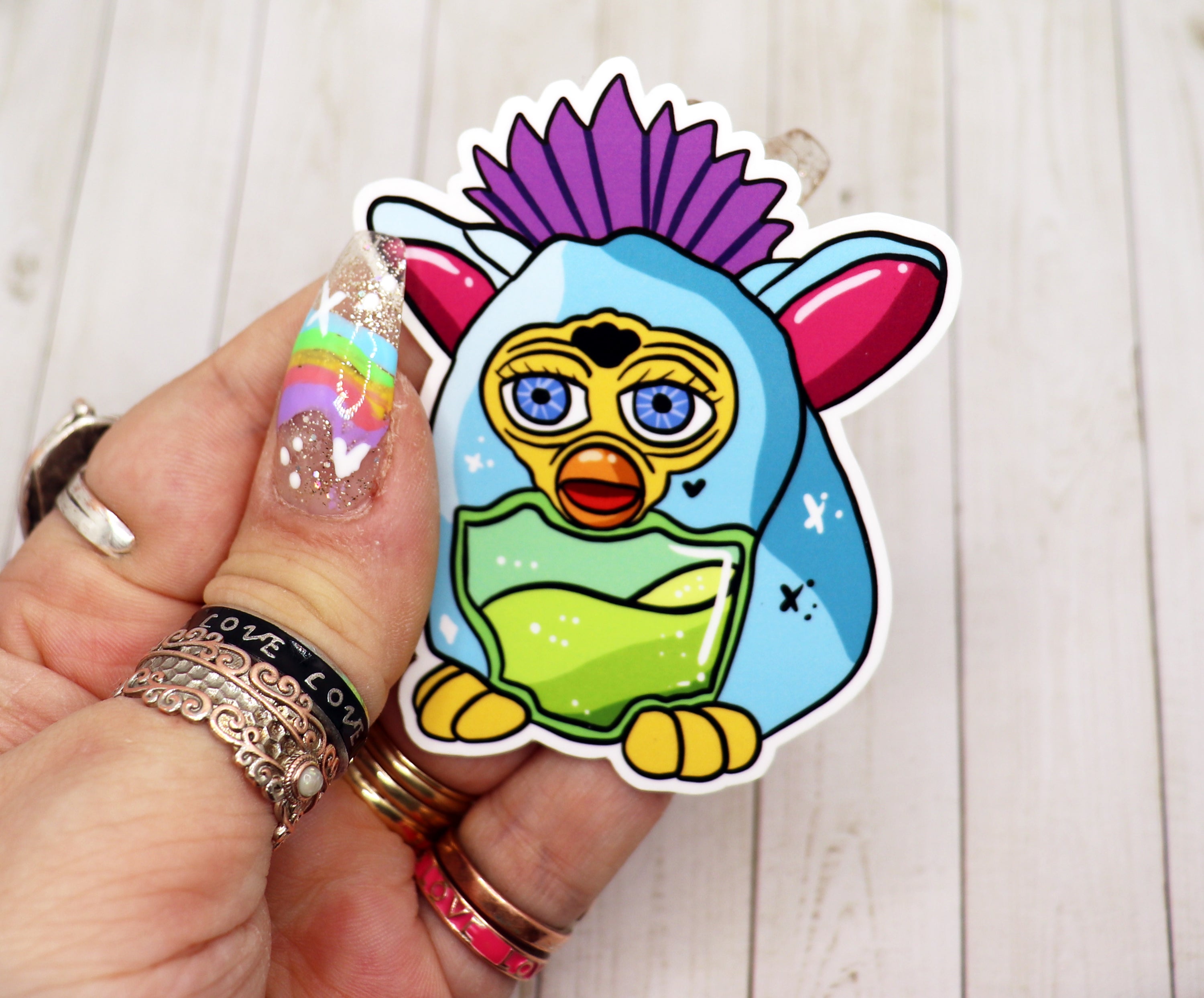 A colorful Furby Vinyl Sticker featuring a playful design, perfect for personalizing various items.