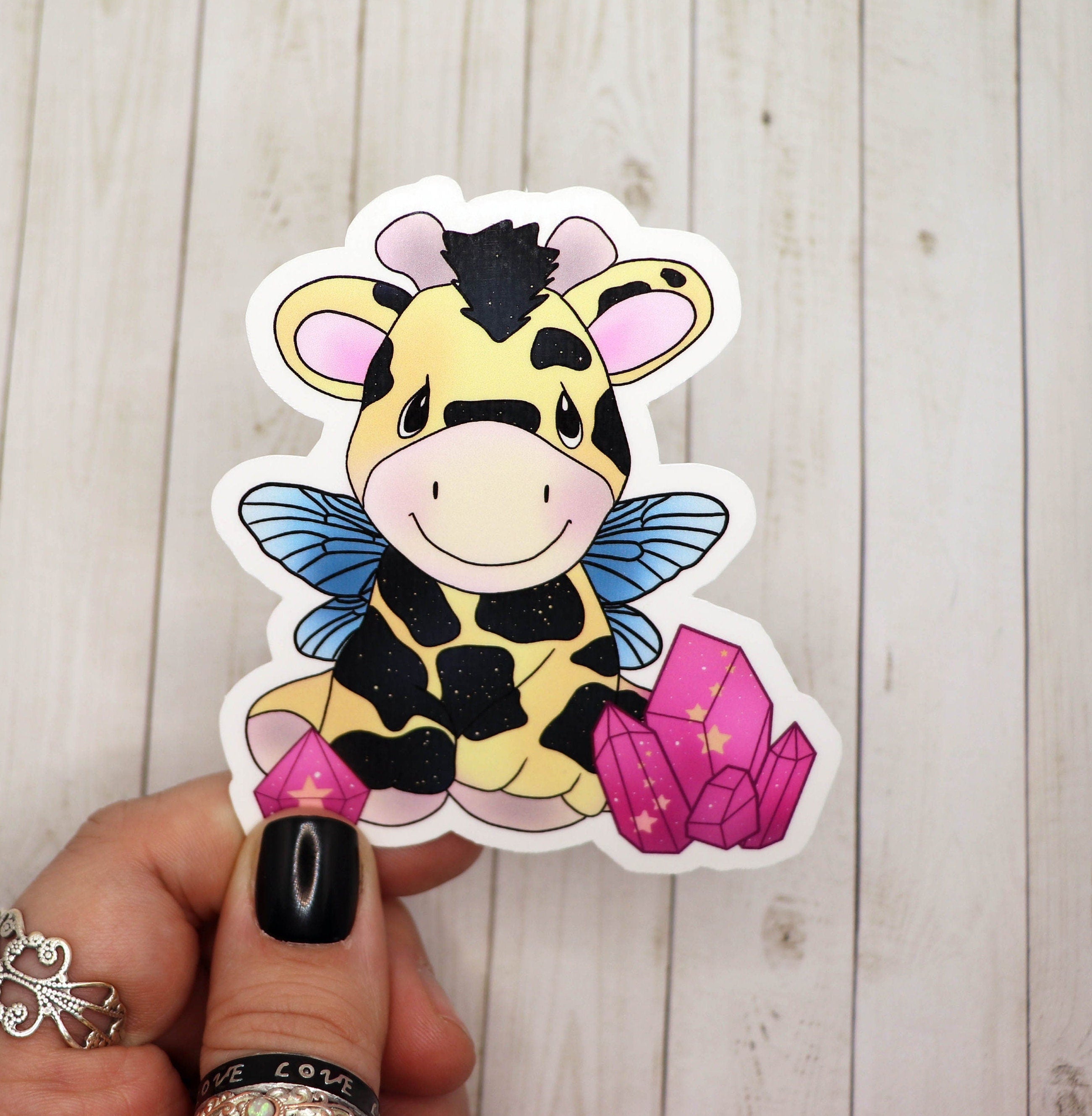 A colorful sticker featuring a giraffe with fairy wings, perfect for decorating various items.