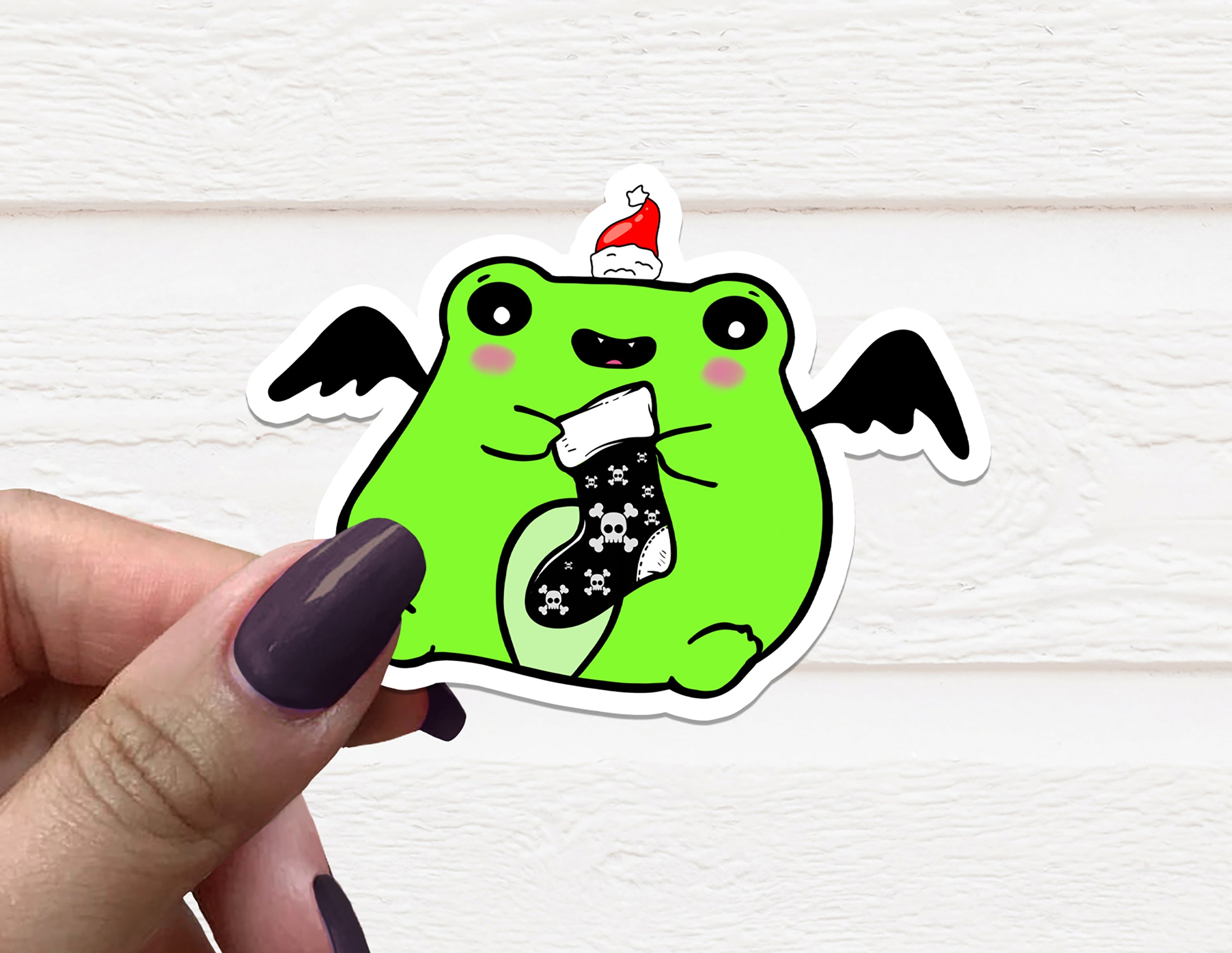 A Gothic Christmas Frog Vinyl Sticker featuring a whimsical frog design in festive colors, perfect for holiday decorations.