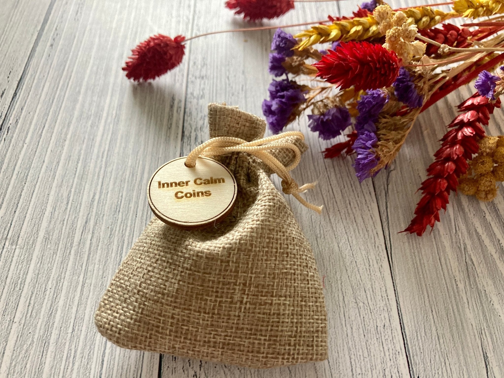 A collection of Inner Calm Coins in a jute bag, showcasing their wooden texture and mindfulness messages.