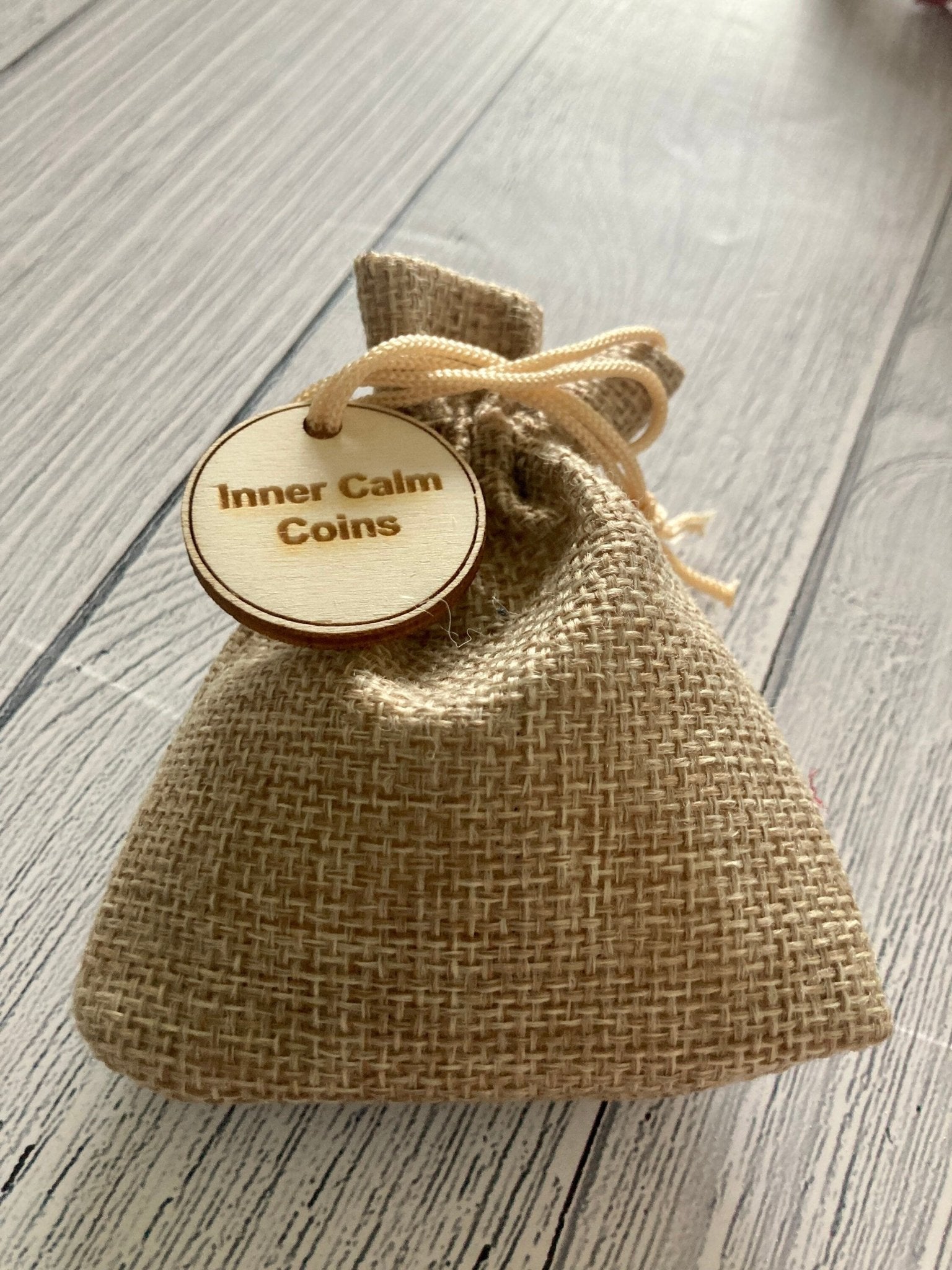 A collection of Inner Calm Coins in a jute bag, showcasing their wooden texture and mindfulness messages.