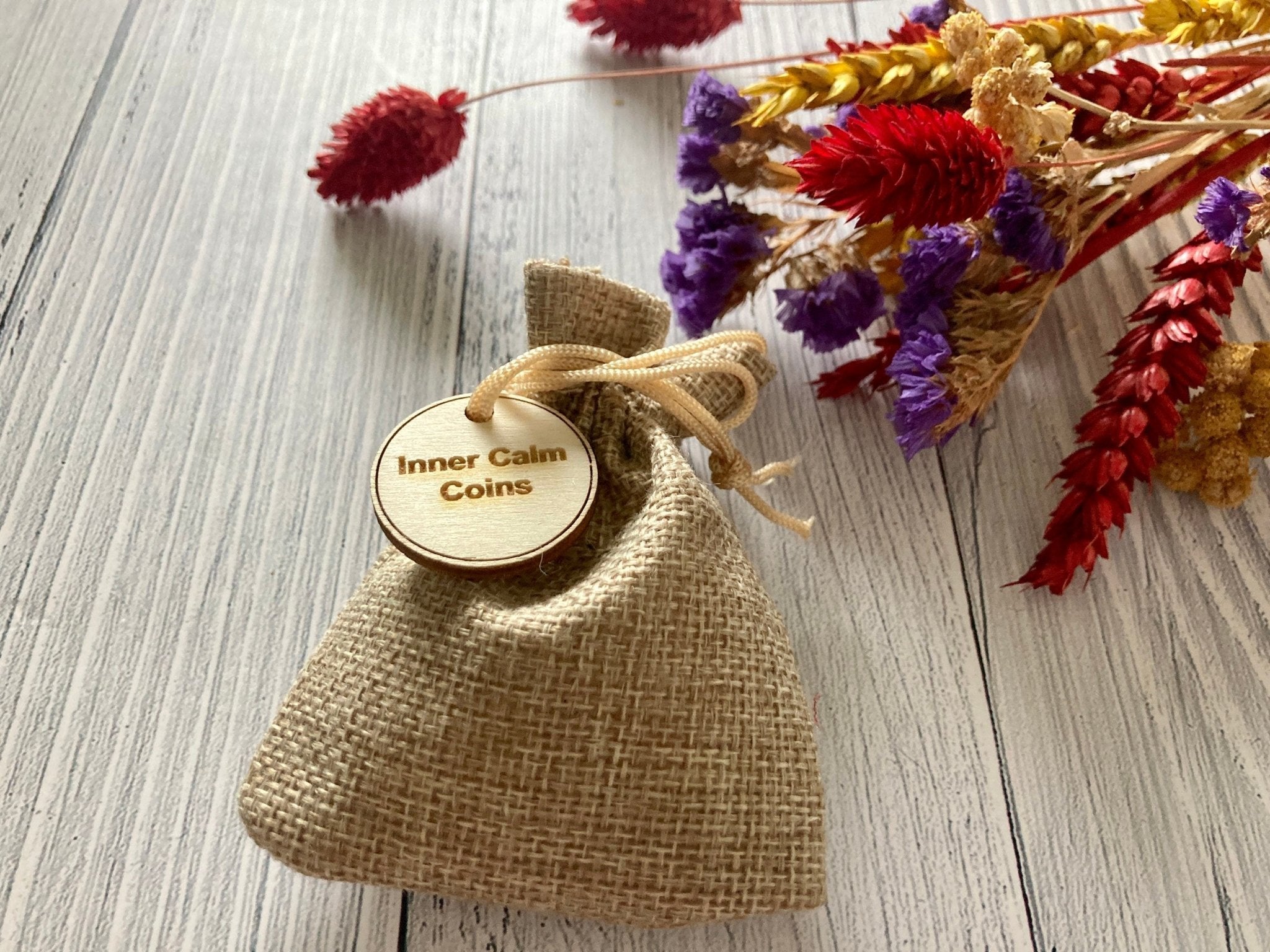 A set of 8 handmade wooden Inner Calm Coins in a jute bag, designed for mindfulness and anxiety relief.