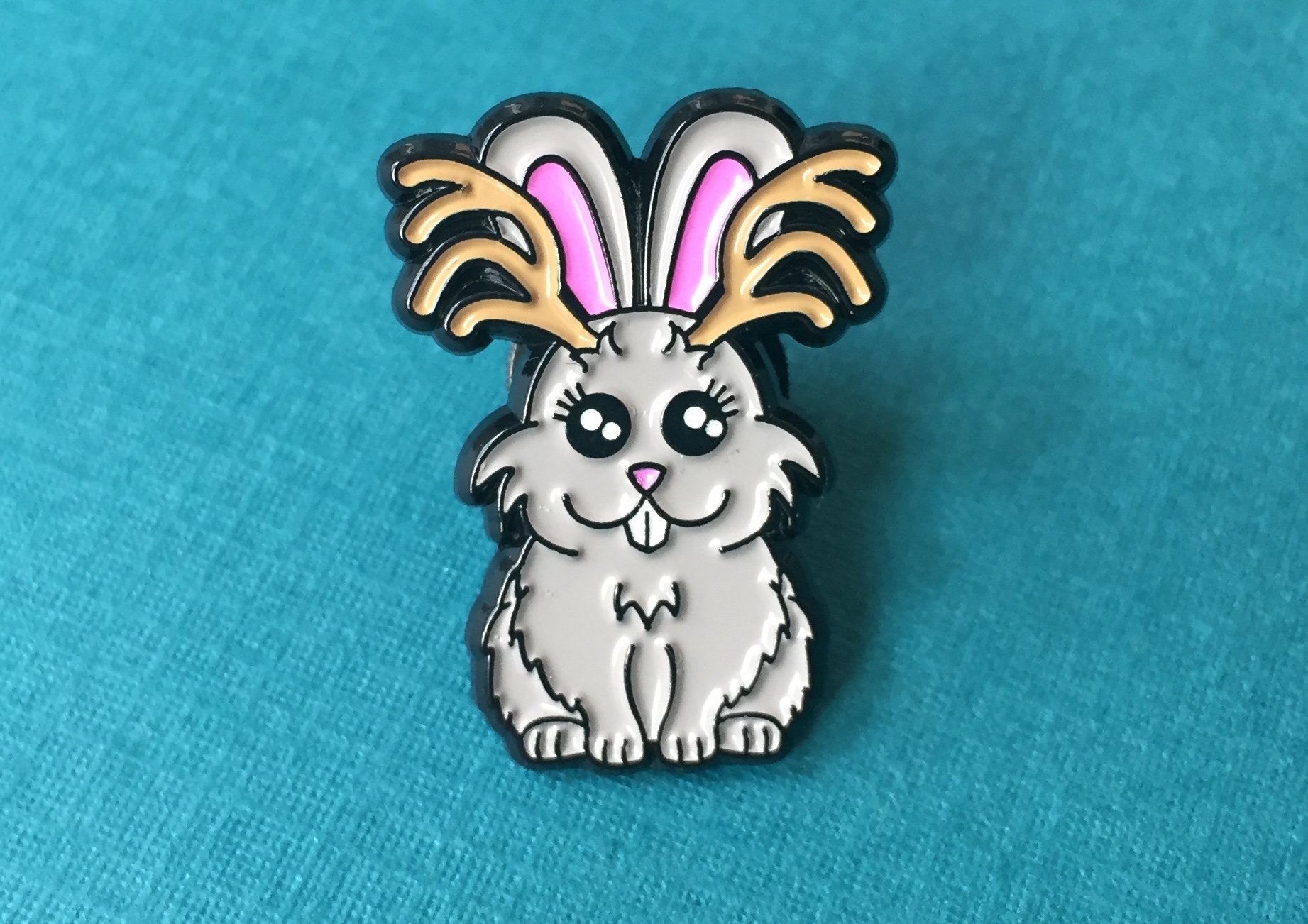 A colorful 1-inch soft enamel pin featuring a whimsical Jackalope design from the Cryptid Collection, showcasing intricate details and vibrant colors.