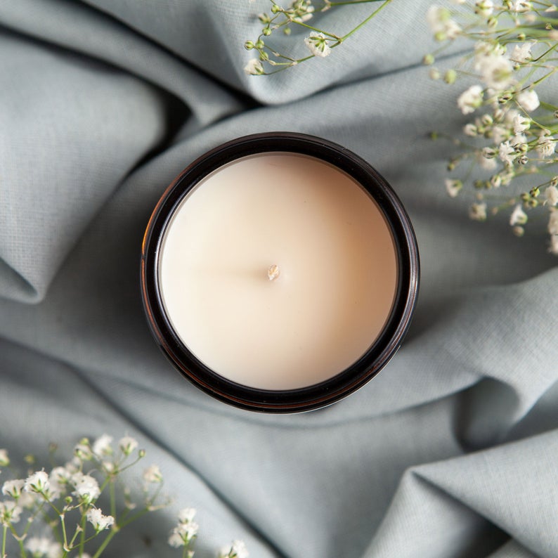 Keep Cozy & Hygge candle in amber glass jar with gold lid, featuring warm scents of fireside, cashmere, and vanilla.