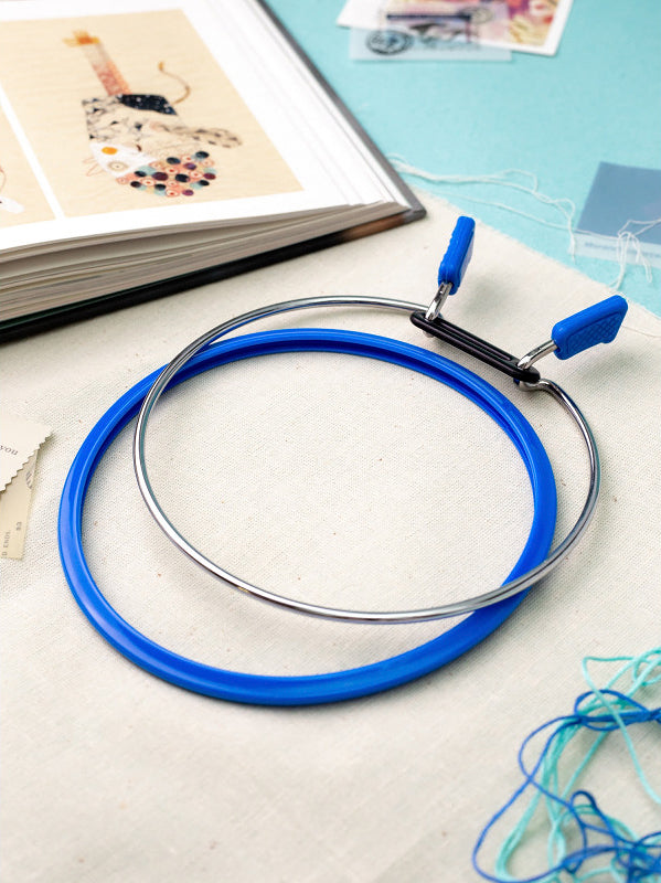 Nurge Large Spring Metal Embroidery Hoop in deep blue, showcasing its two-part design with a plastic ring and flexible metal ring.