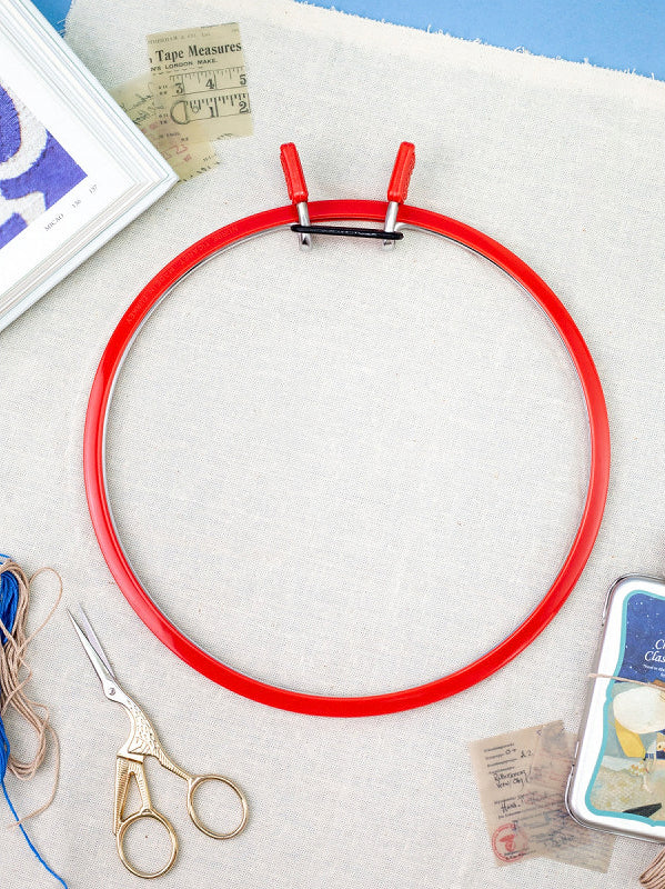 Large Spring Metal Embroidery Hoop by Nurge in deep red, showcasing its two-part design with a plastic ring and flexible metal ring.