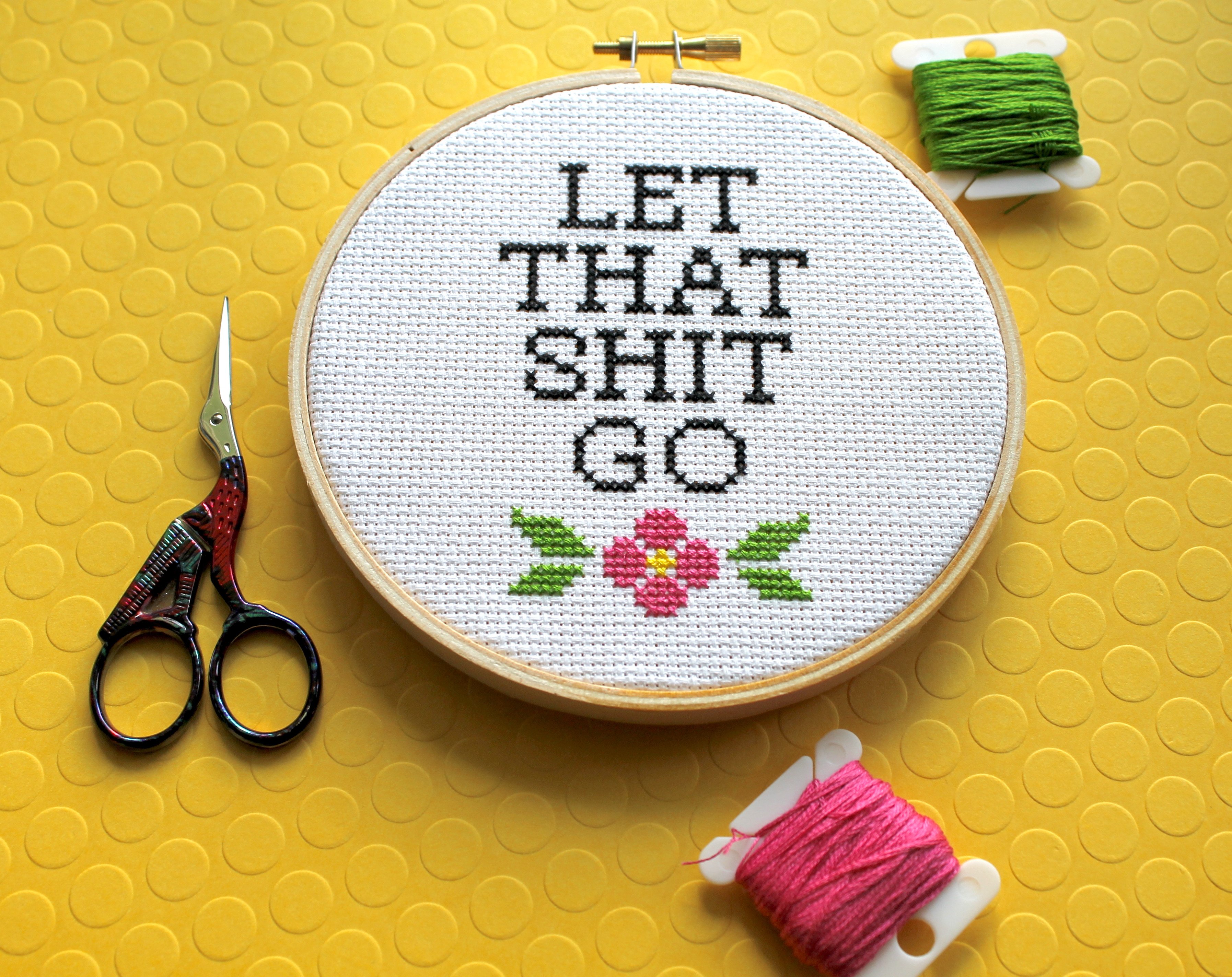 Let That Sh*t Go Counted Cross Stitch DIY Kit featuring floral elements and text, complete with all necessary supplies.