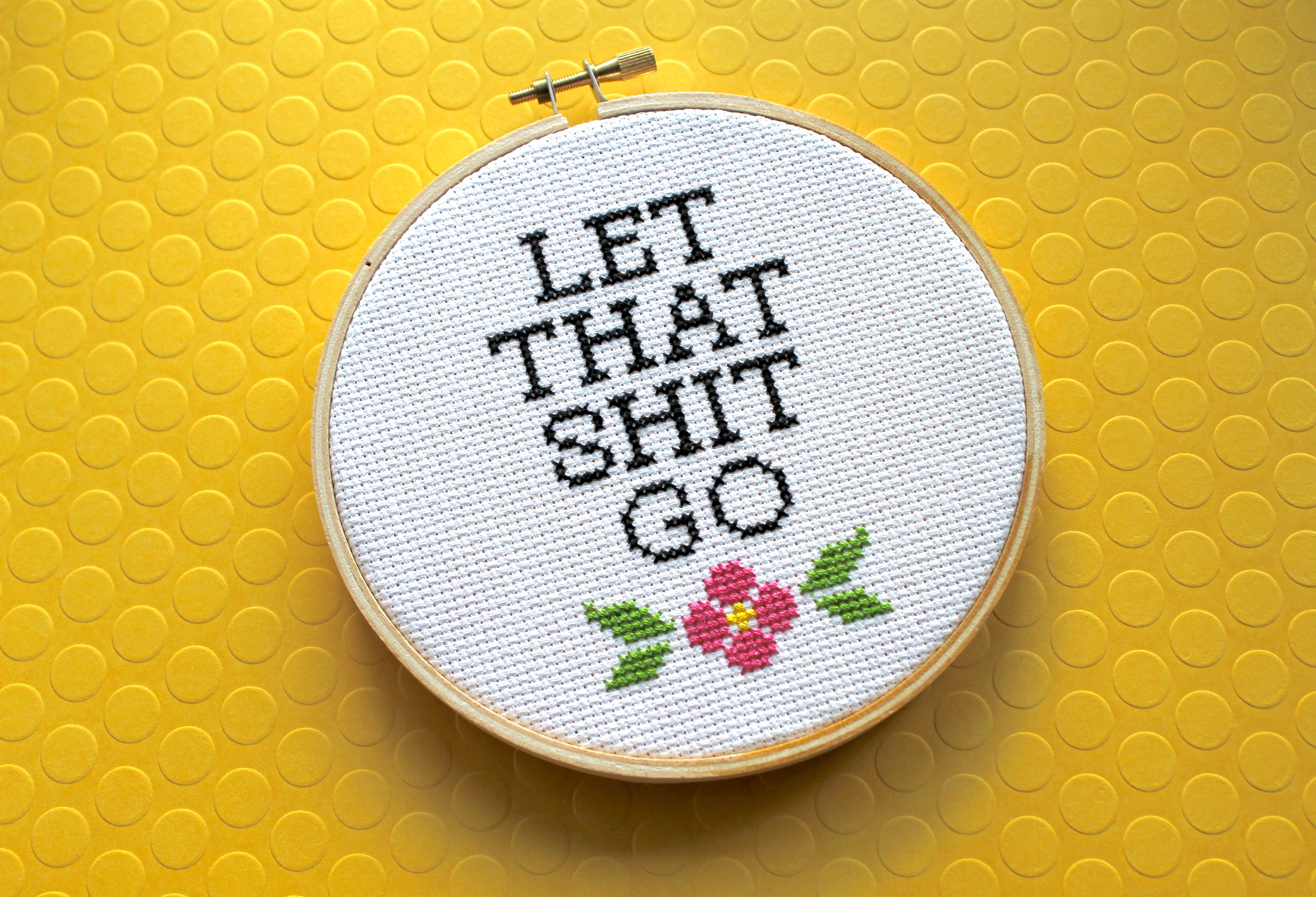 Let That Sh*t Go Counted Cross Stitch DIY Kit featuring floral elements and text, complete with all necessary supplies.