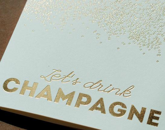 A stylish 'Let's Drink Champagne' greeting card featuring gold foil accents, folded design, and a lined envelope, perfect for various celebrations.