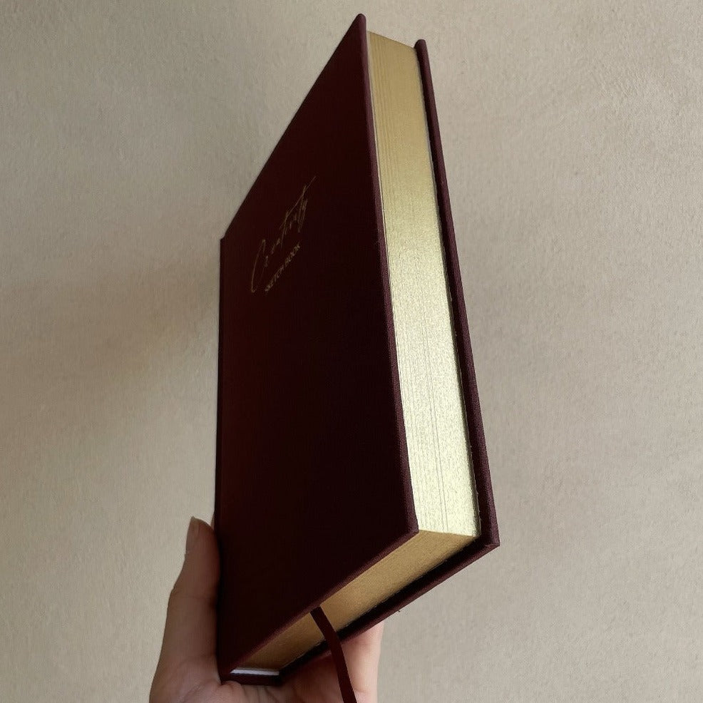 Luxury linen sketchbook with thick paper and gold edging, featuring a silk ribbon bookmark and protective hardback sleeve.