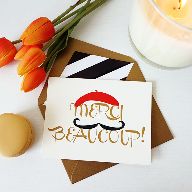 A stylish 'Merci Beaucoup' thank you card with a lined envelope, featuring debossed finishing and elegant design.